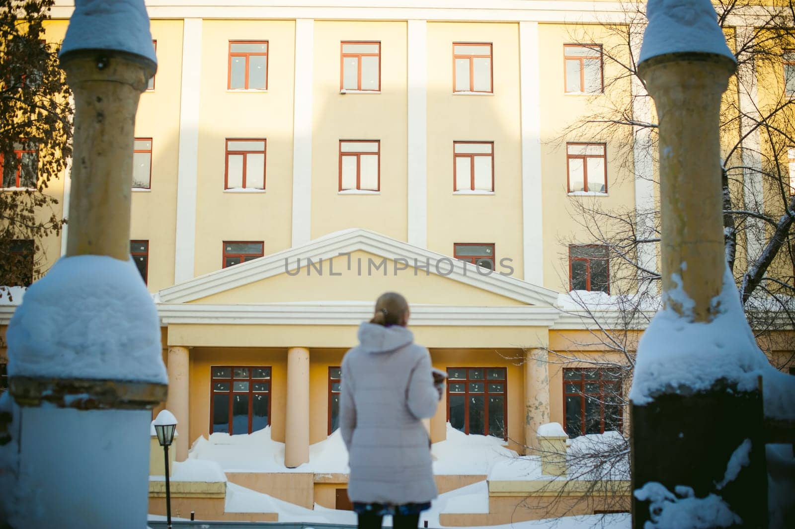 young woman dressed in warm clothes drinking takeaway coffee from the cup on the street in winter