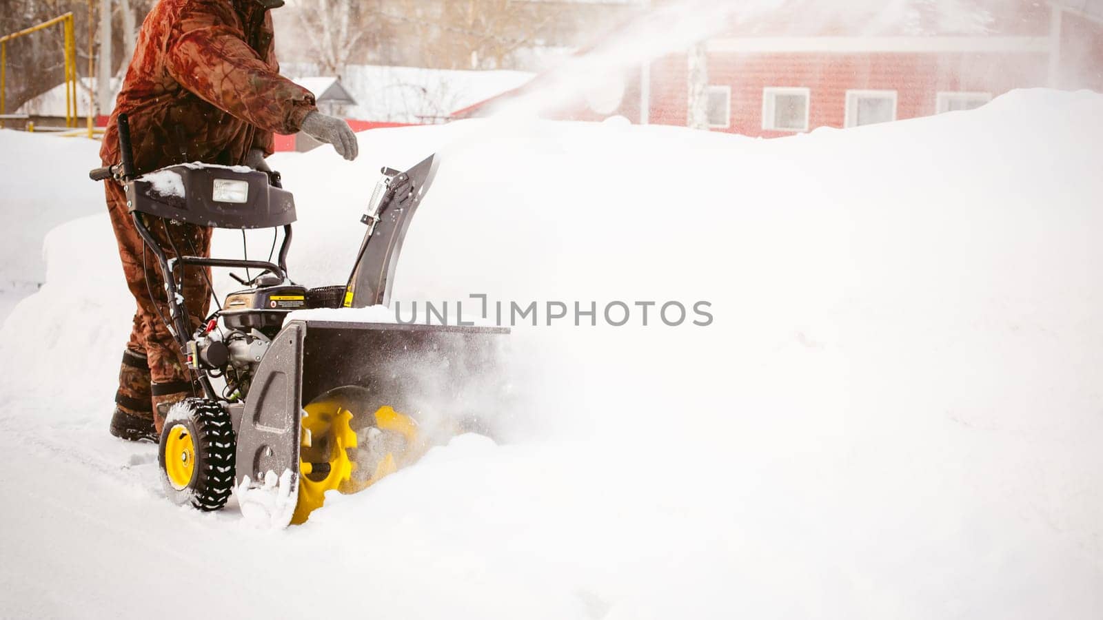 man operating snow blower to remove snow on driveway