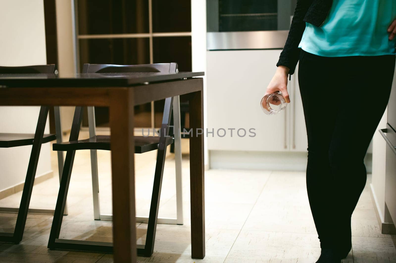 blonde woman in the kitchen holding a glass beaker, pour the water from the kettle to quench their thirst