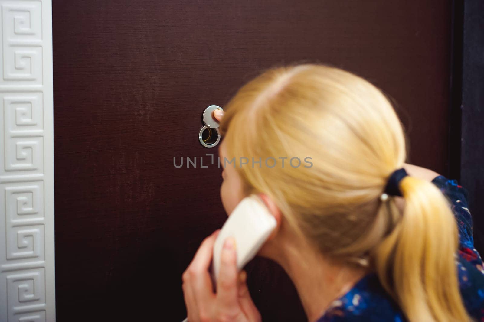 blonde woman answers the intercom call, hold the phone to his ear, waiting for the arrival of the long-awaited guest. Being in apartment near front door