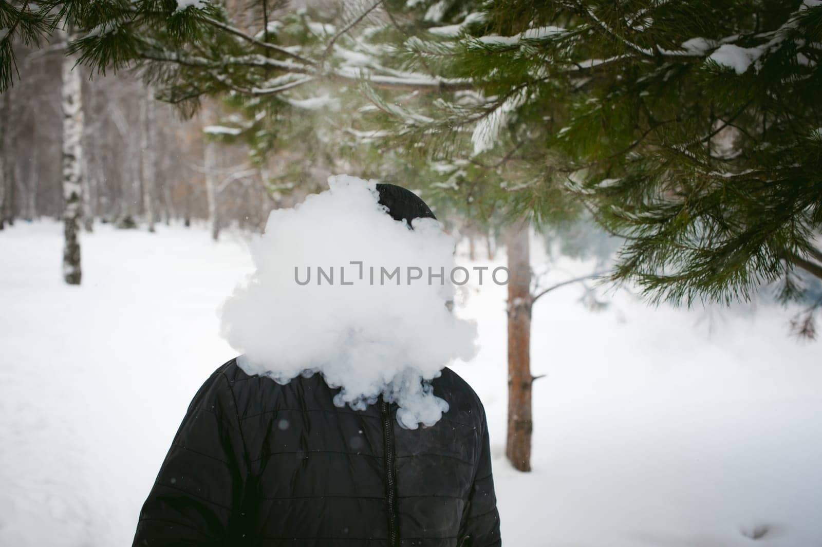 a young man with a beard, smokes an electronic cigarette, outdoors in winter snow