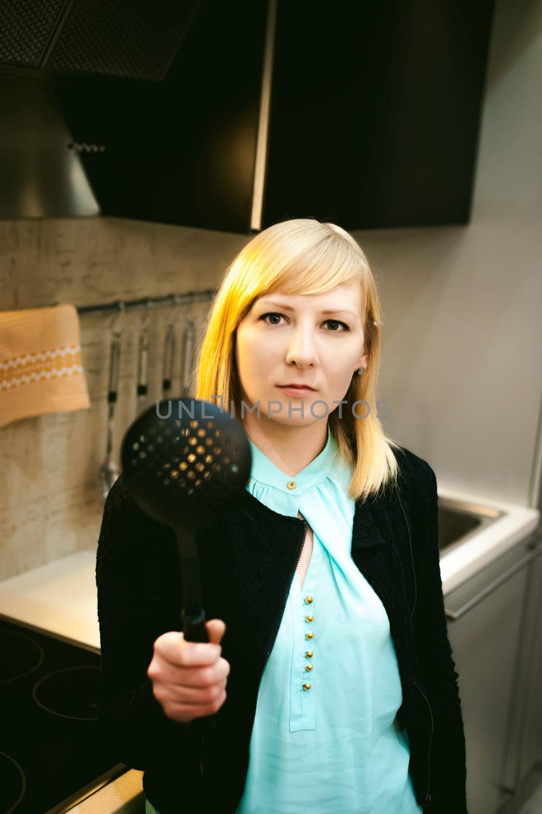 blonde woman in the kitchen, holding a cutlery