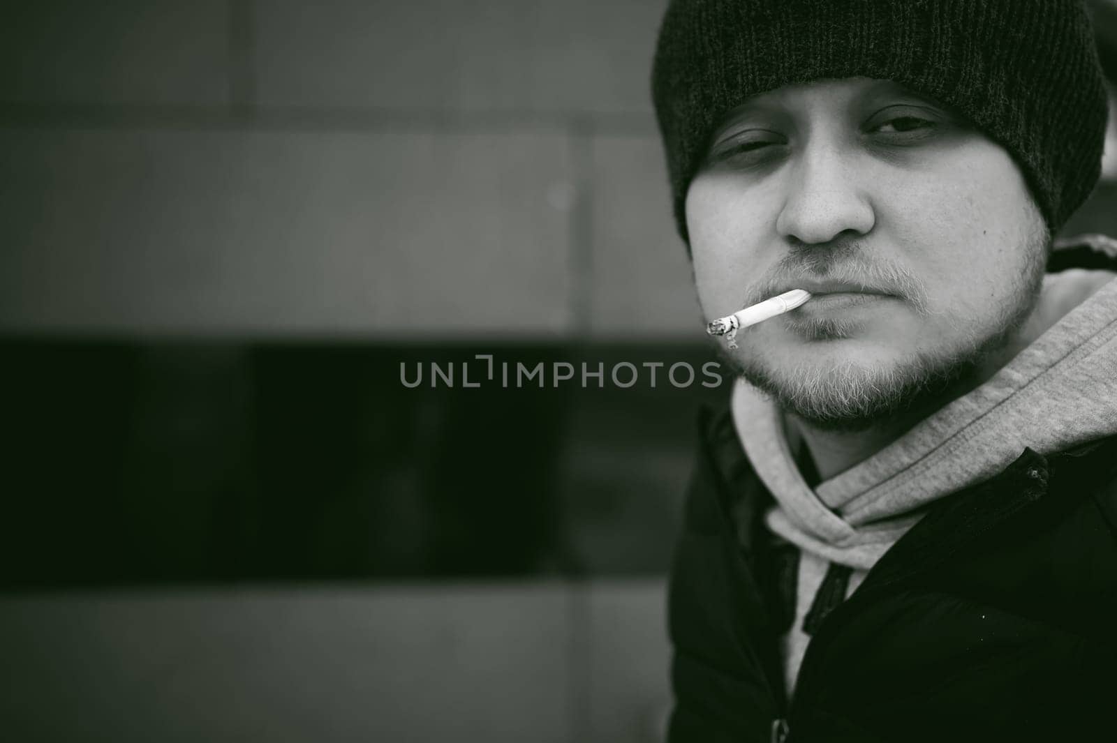 Portrait of a man with a beard with a mustache, smoking a cigarette, with an emotional face in the open air