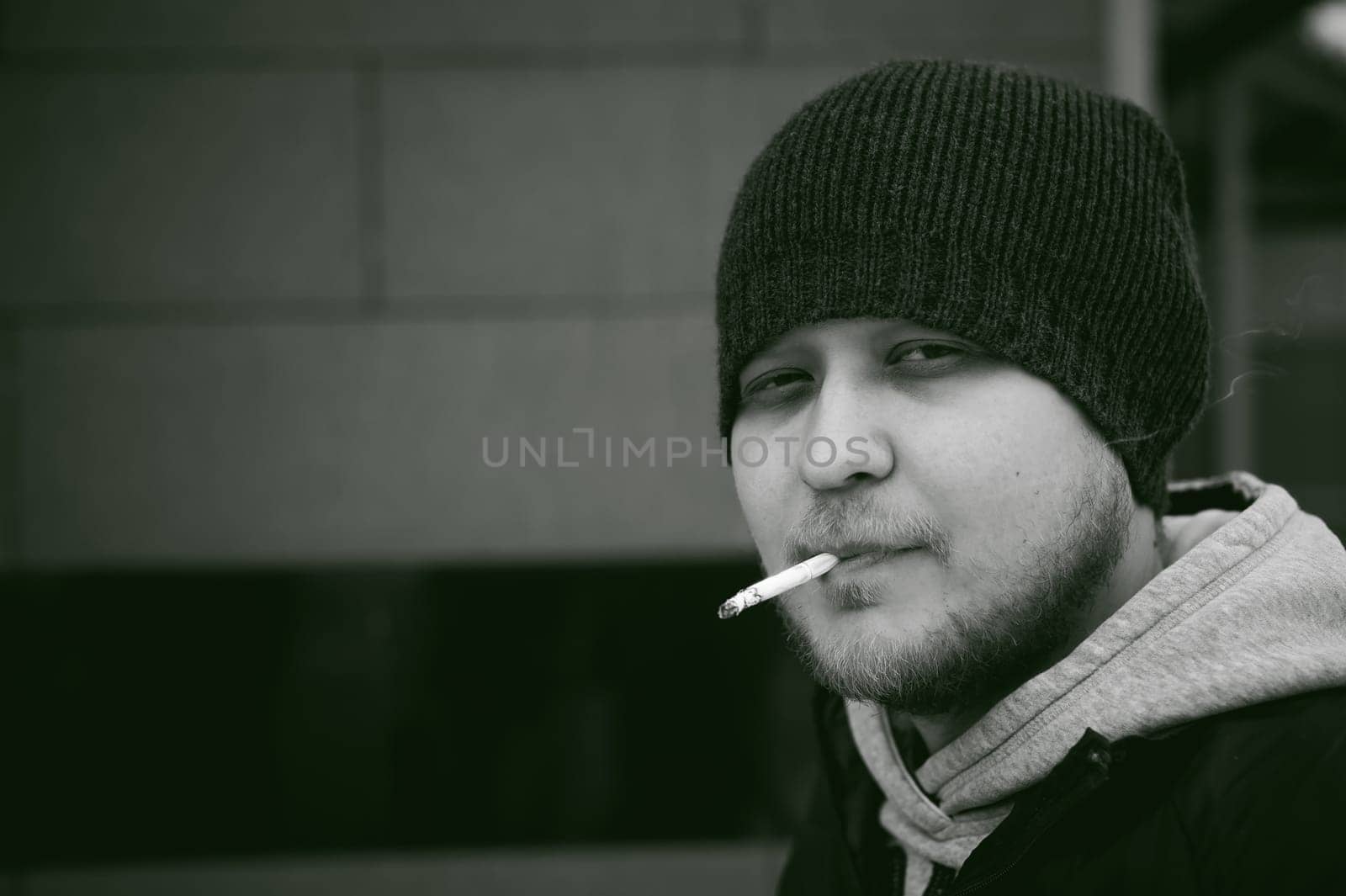 Portrait of a man with a beard with a mustache, smoking a cigarette, with an emotional face in the open air