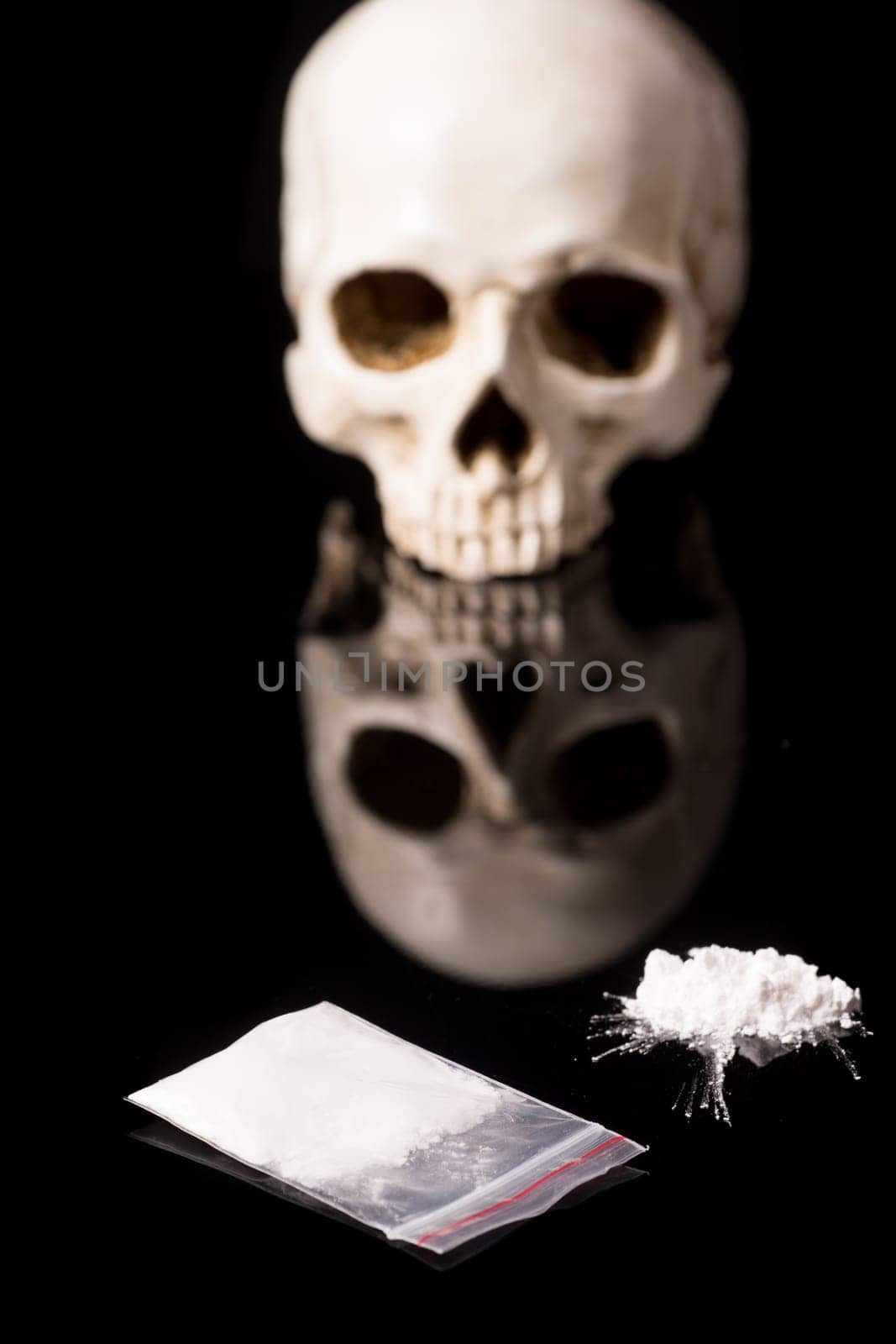cocaine, Herion or other illegal drugs that are sniffed by means of a tube or injected with a syringe and Skull, isolated on black glossy background