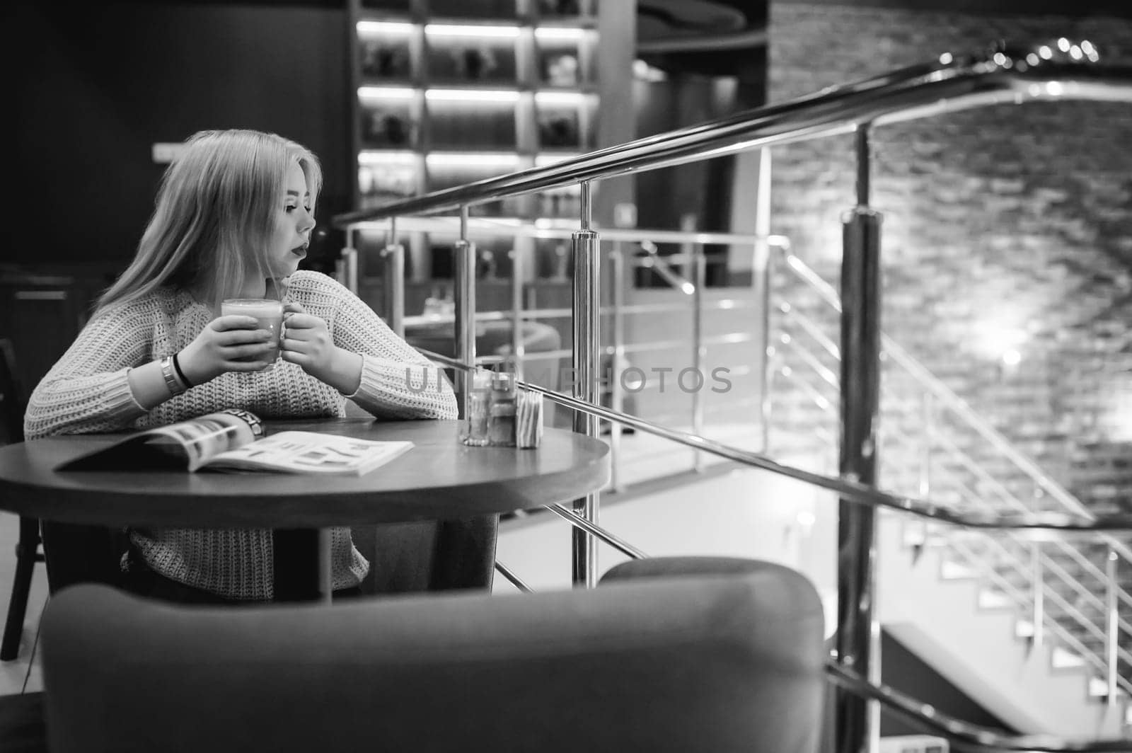 Picture of young lady sitting in cafe while reading magazine And drinks coffee
