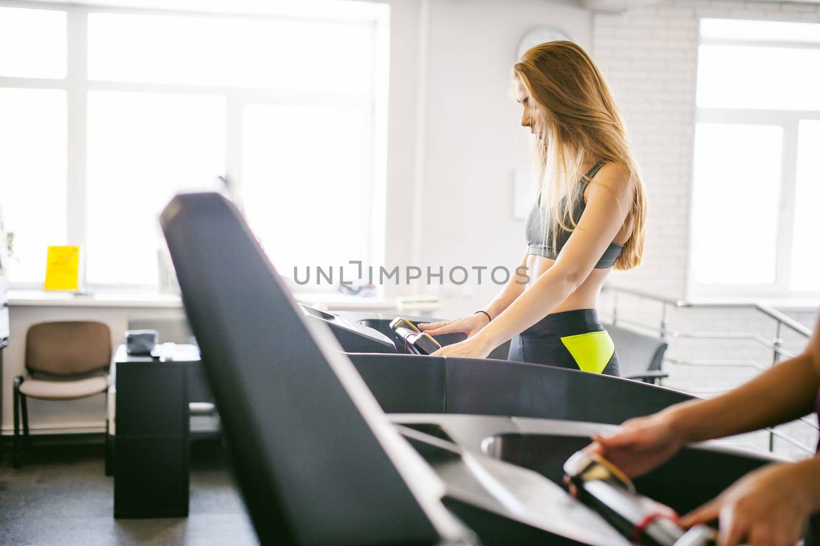 young woman is engaged fitness in gym. Performs cardio load on treadmill, running and walking with acceleration. sport, fit, lifestyle, technology and people concept