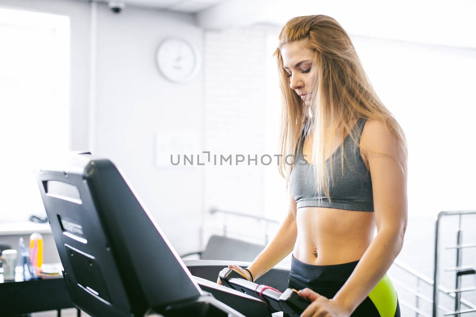 young woman is engaged fitness in gym. Performs cardio load on treadmill, running and walking with acceleration. sport, fit, lifestyle, technology and people concept
