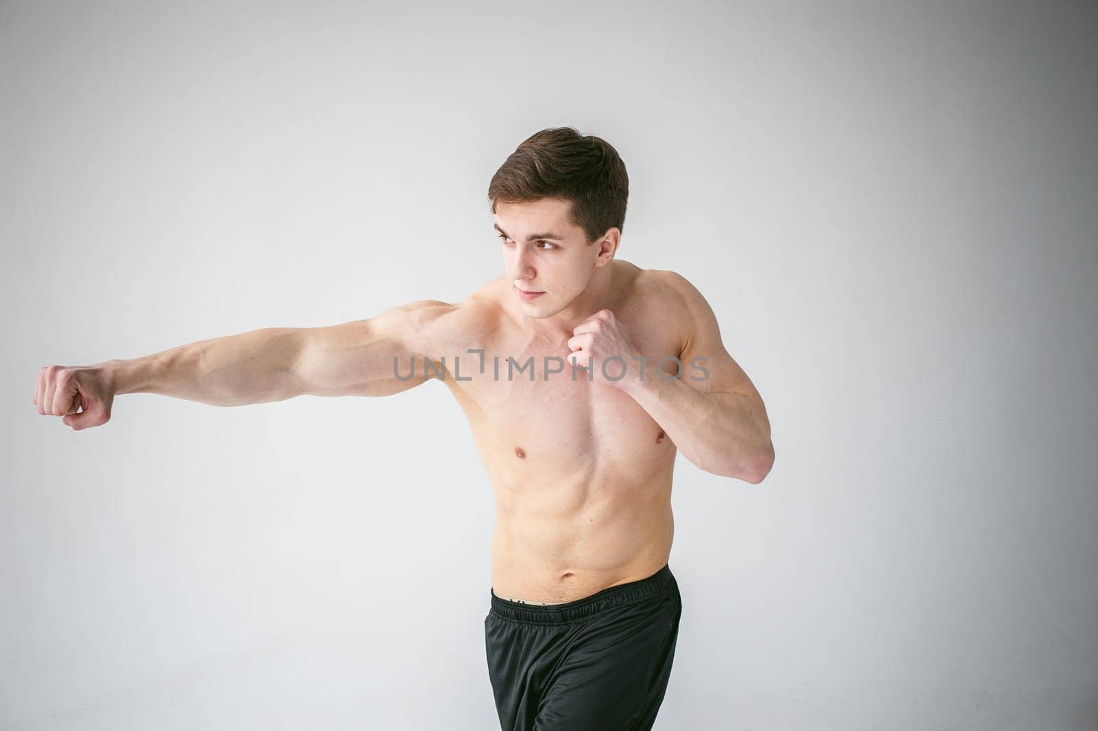 young sexy handsome men of strong Athlete's body with bare torso, Dressed black sports shorts, portrait of studio of light-skinned strong man standing in fighting stance, straining powerful hands