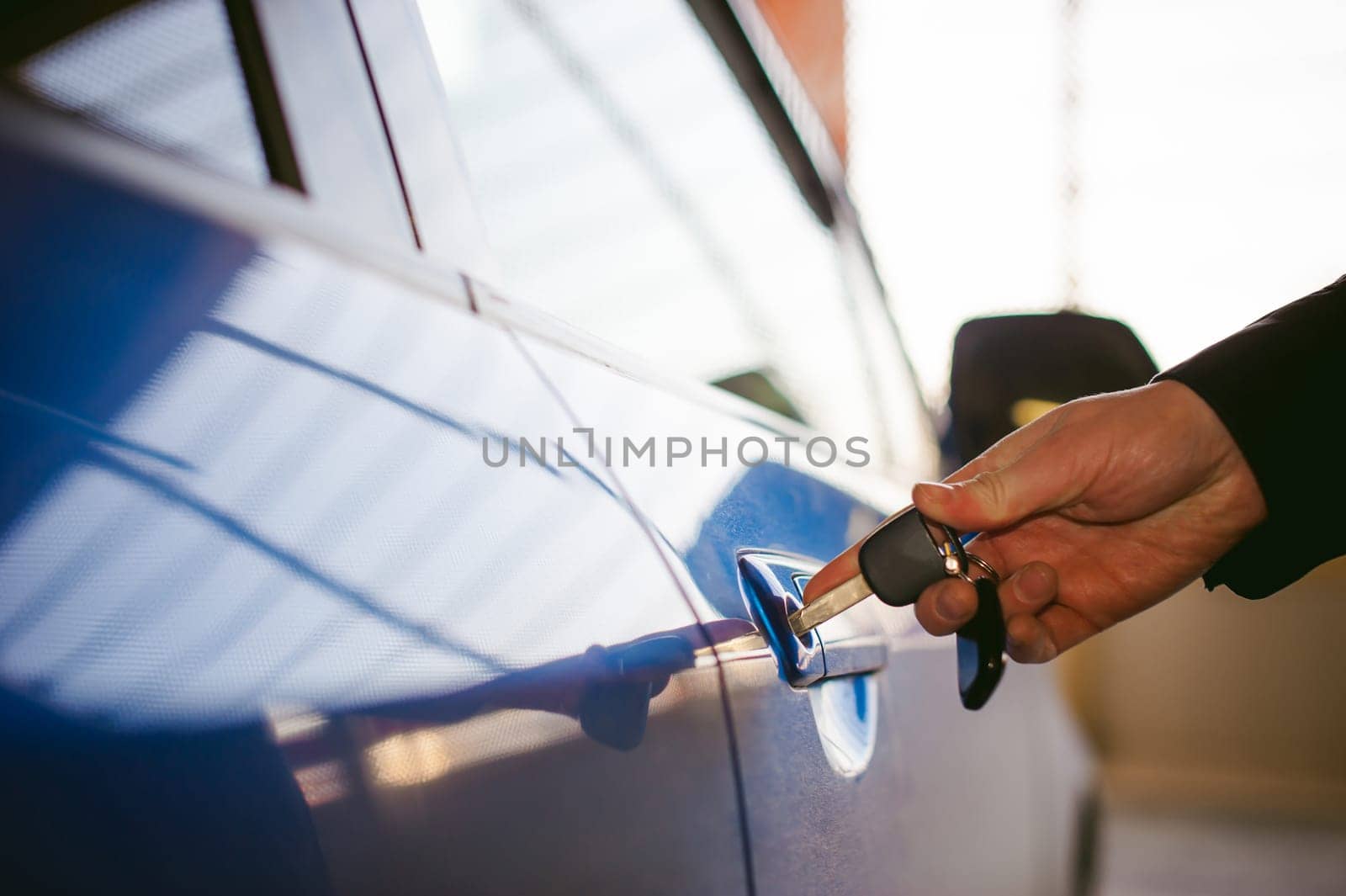 Woman in parking lot on blue car background. Opens door with key