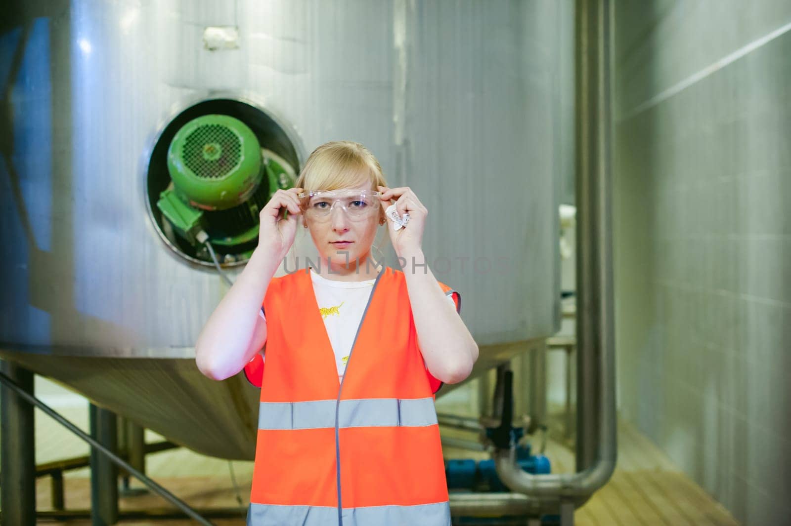 Female worker on beer factory. portrait woman in robe, standing on background line Food production, Inspection management control Equipment for production and bottling finish product end-user buyer