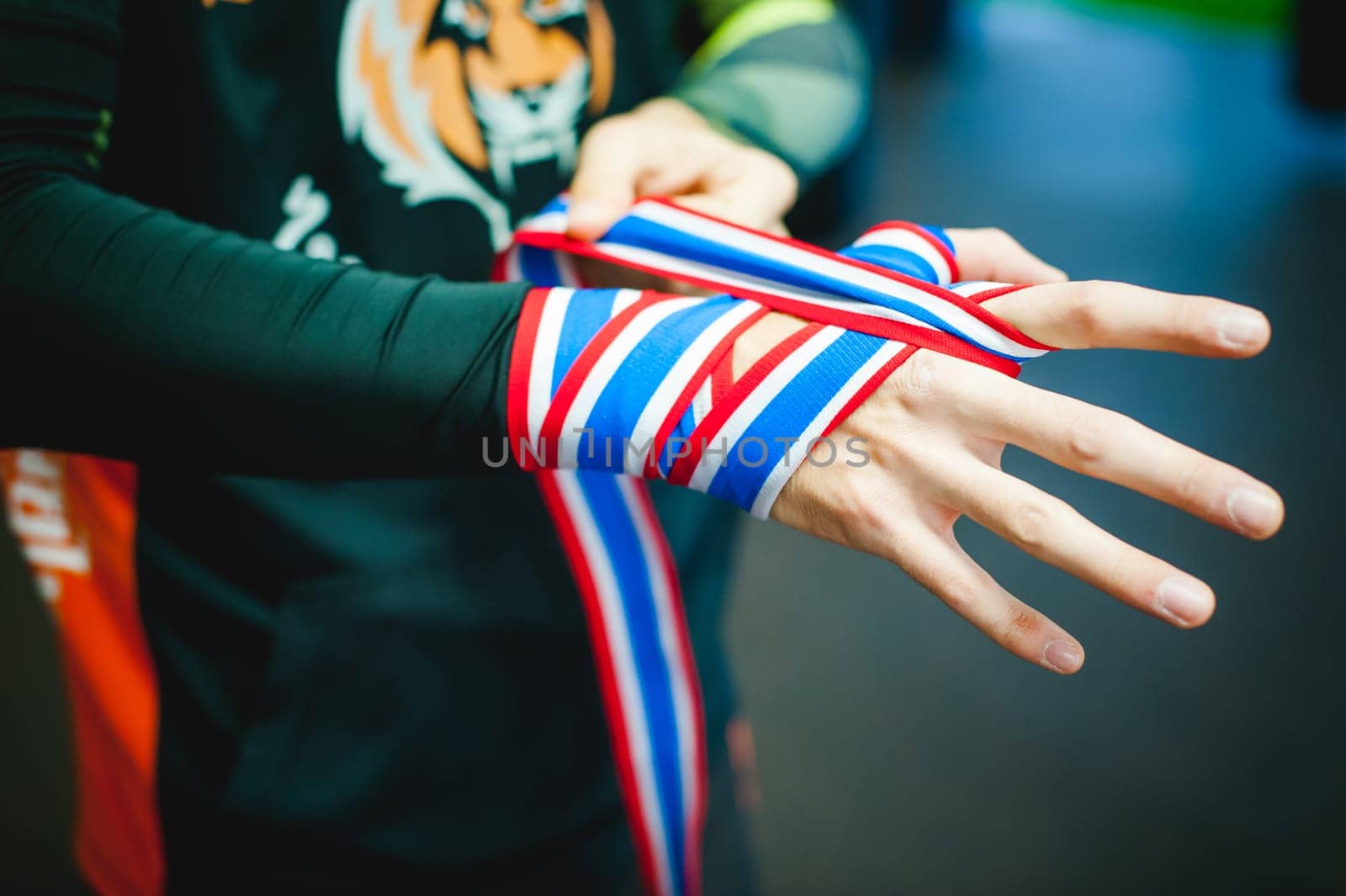 Professional Muay Thai and K1 fighter. Male boxer in training sportswear, an exercise in the sports hall, Preparation Boxing bandage