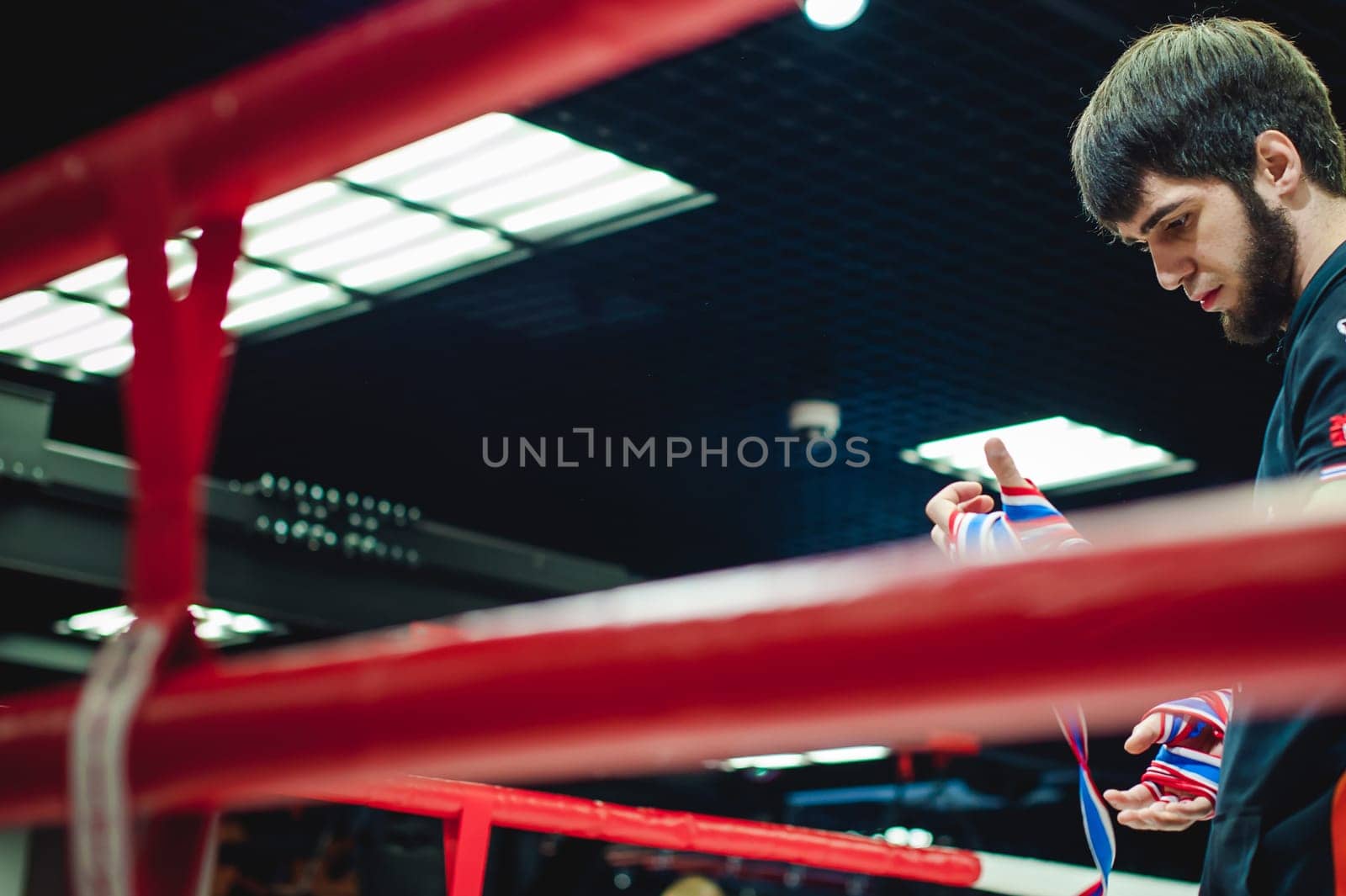 Professional Muay Thai and K1 fighter. Male boxer in training sportswear, an exercise in the sports hall, Preparation Boxing bandage