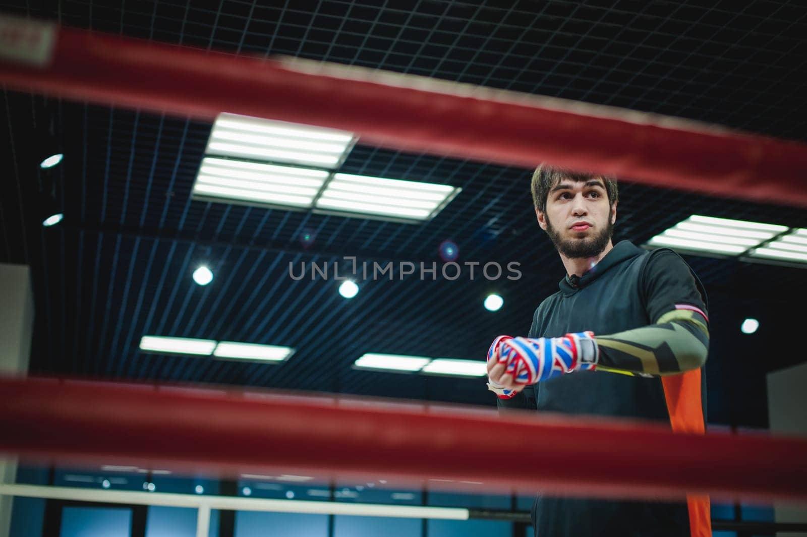 Professional Muay Thai and K1 fighter. Male boxer in training sportswear, an exercise in the sports hall, Preparation Boxing bandage