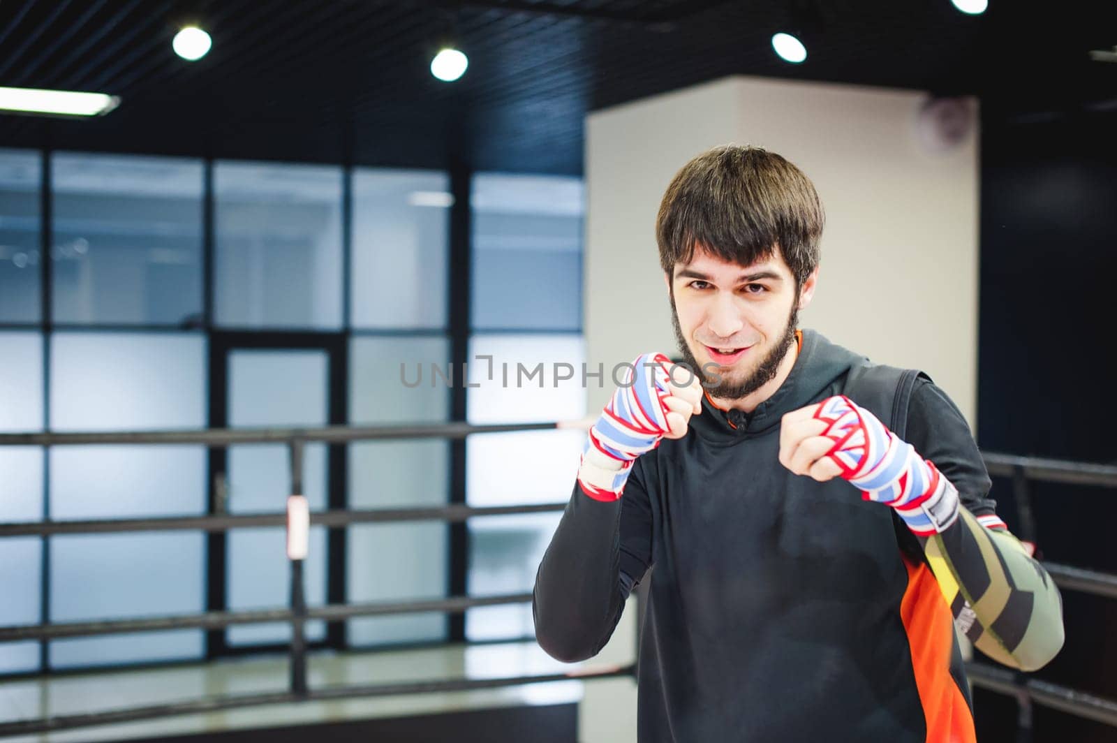 Professional Muay Thai fighter. Male boxer in training sportswear, an exercise in sports hall, fight with a shadow in ring, Strike testing