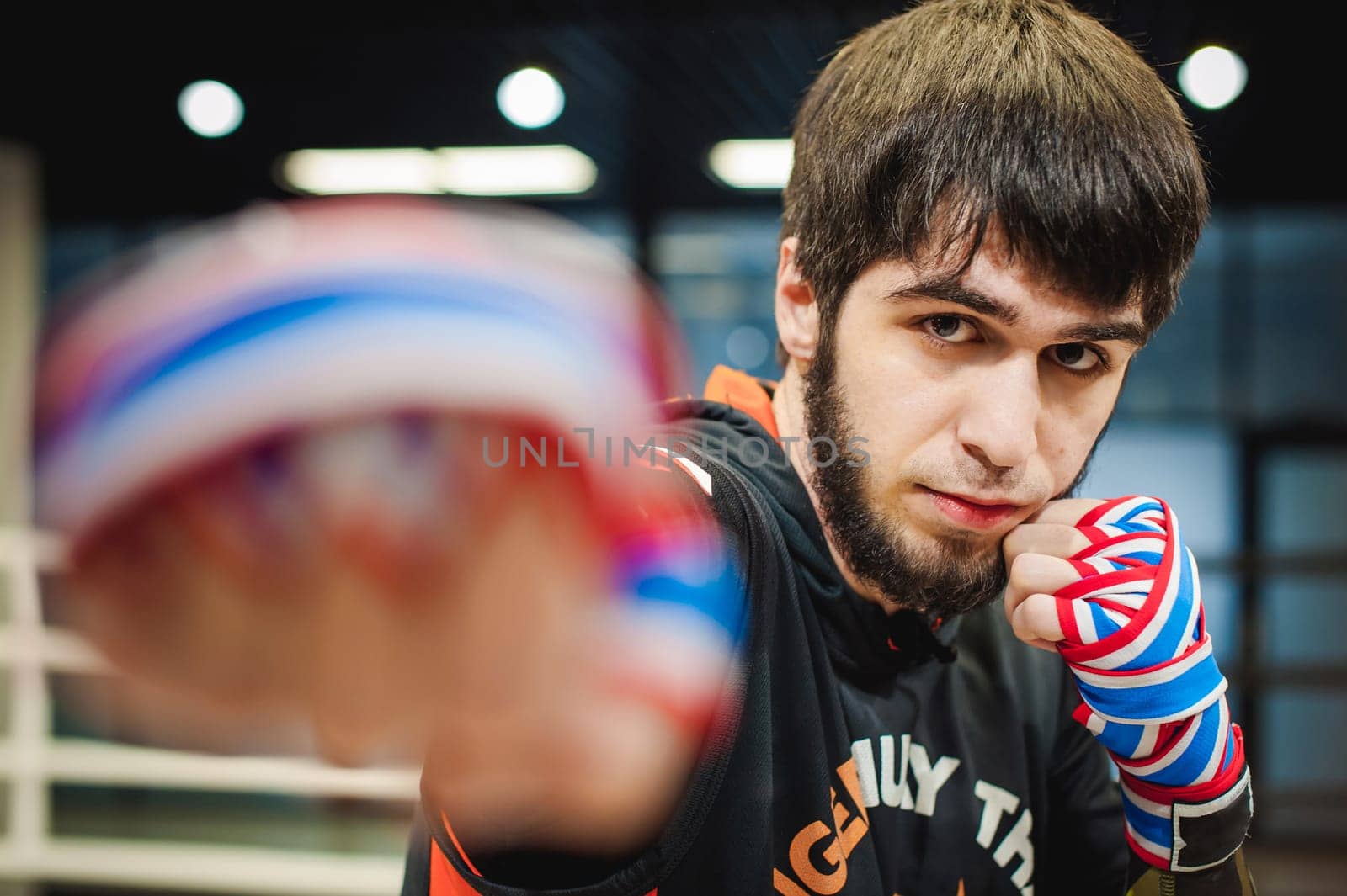 Professional Muay Thai and K1 fighter. Male boxer in training sportswear, an exercise in the sports hall, Preparation Boxing bandage