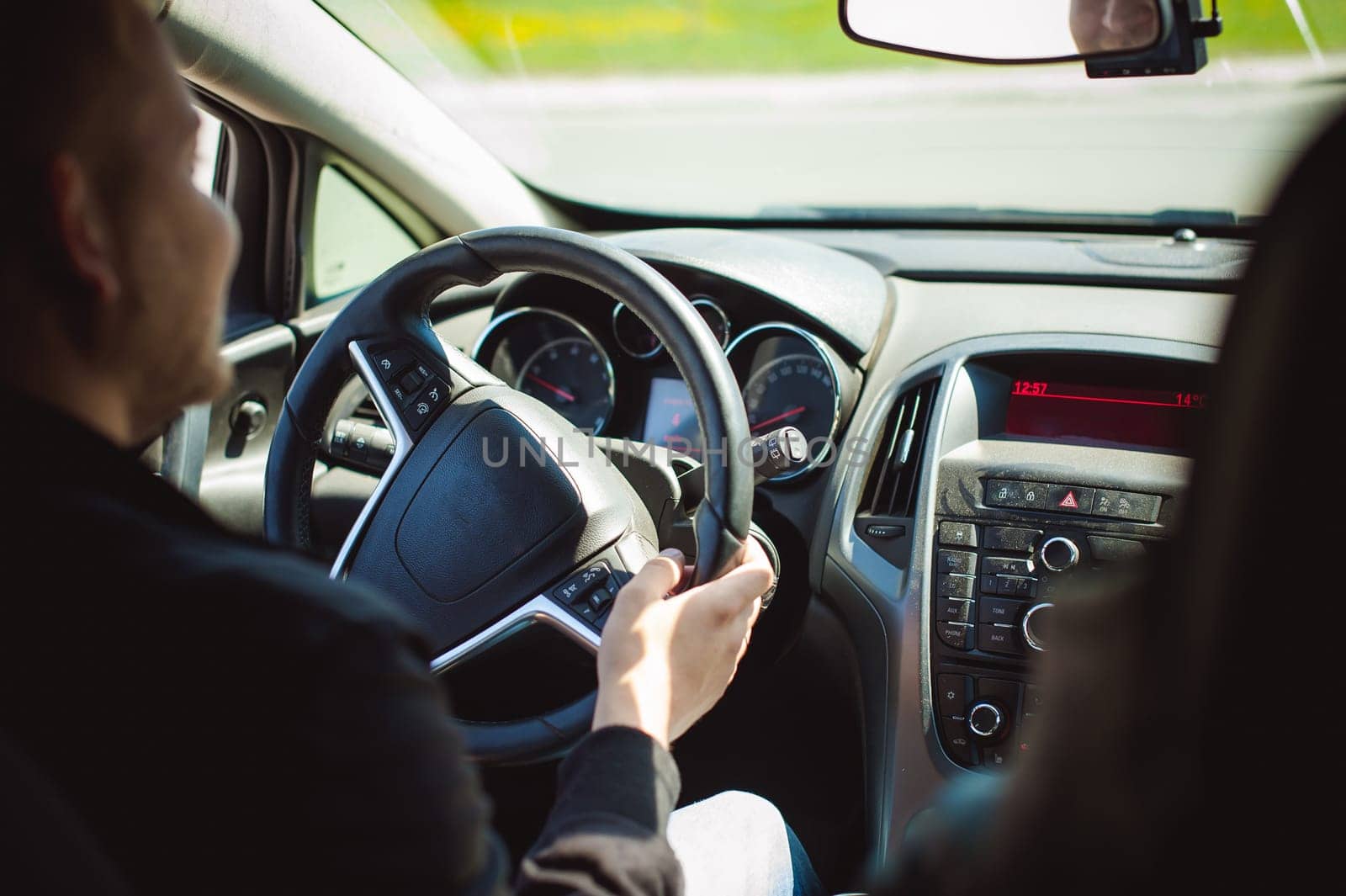 young bearded man driving a car, inside cabin rides, looking at road, driving, holding steering wheel.