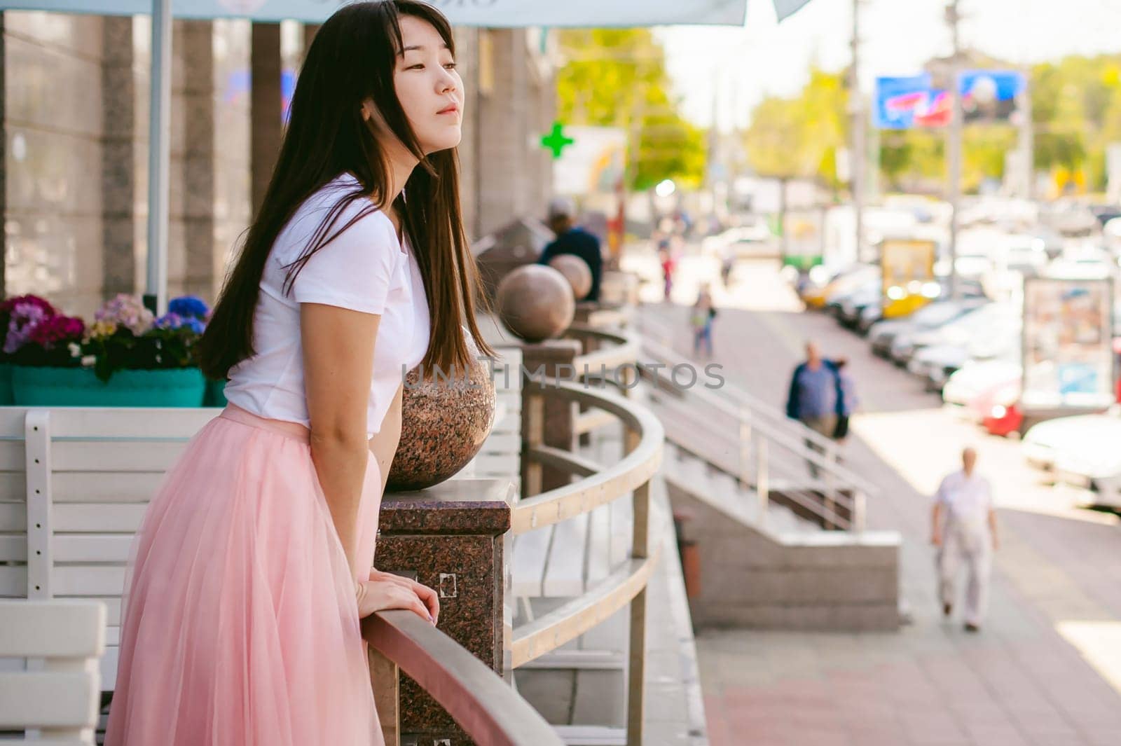 Cute asian young woman in summer cafe outdoors. girl In white T-shirt, with long hair in simple light cozy interior of restaurant Urban style