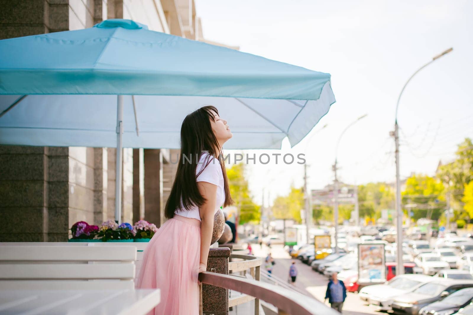 Cute asian young woman in summer cafe outdoors. girl In white T-shirt, with long hair in simple light cozy interior of restaurant Urban style