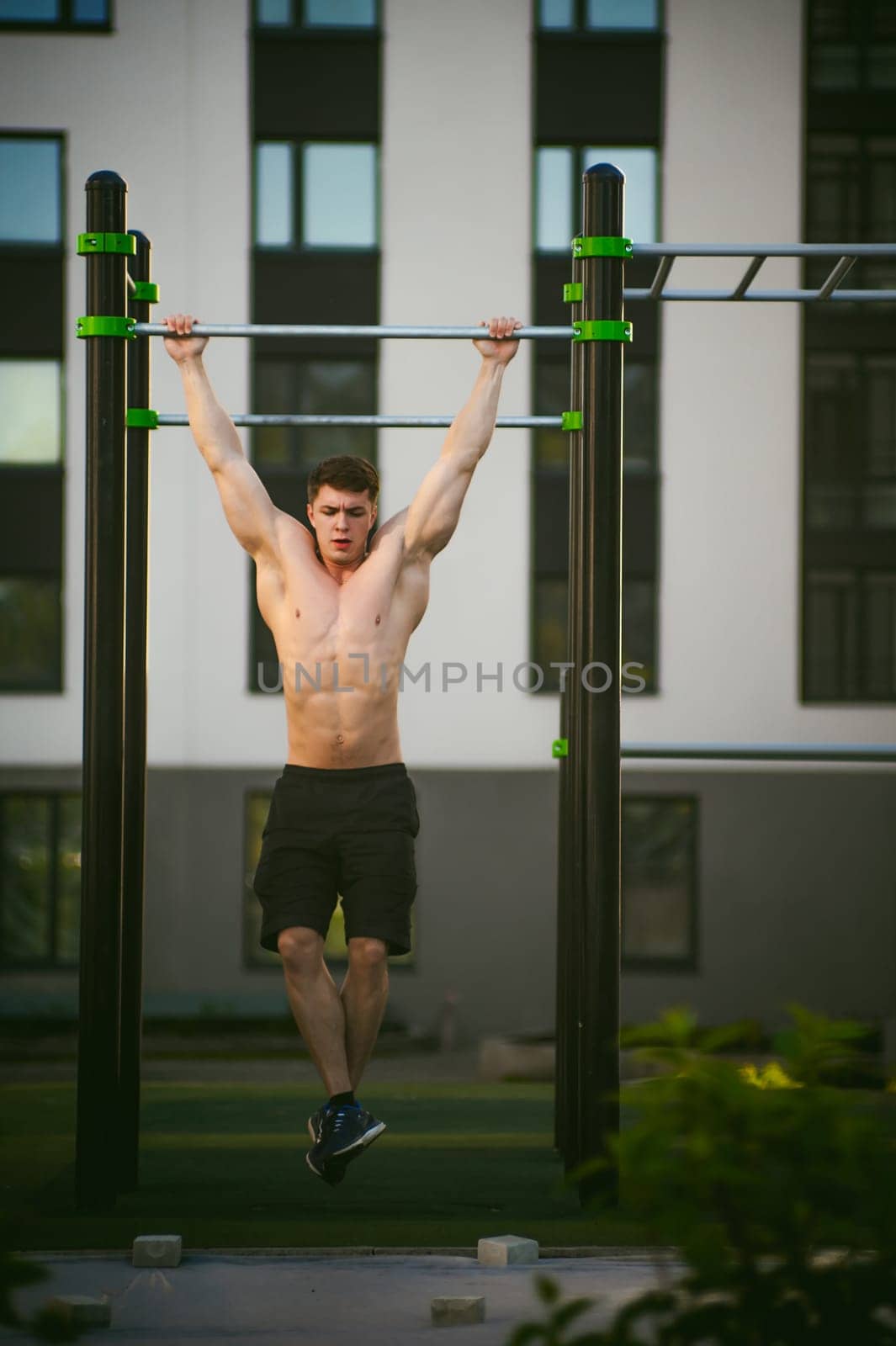 Handsome sexy male bodybuilder athlete man doing crossfit workout in athletic facilities on sunny morning outdoors. Healthy lifestyle concept. Physical preparation of body. pull-up on horizontal bar