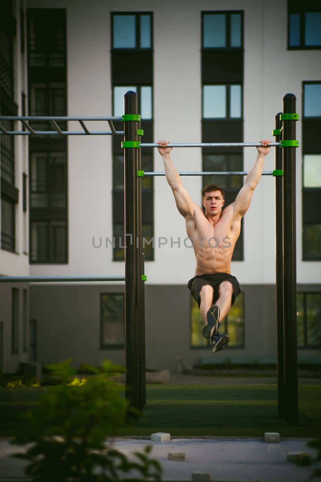 Handsome sexy male bodybuilder athlete man doing crossfit workout in athletic facilities on sunny morning outdoors. Healthy lifestyle concept. Physical preparation of body. pull-up on horizontal bar