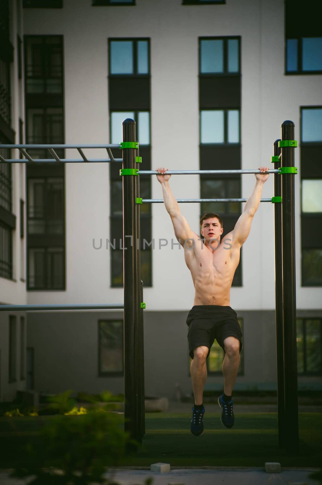 Handsome sexy male bodybuilder athlete man doing crossfit workout in athletic facilities on sunny morning outdoors. Healthy lifestyle concept. Physical preparation of body. pull-up on horizontal bar