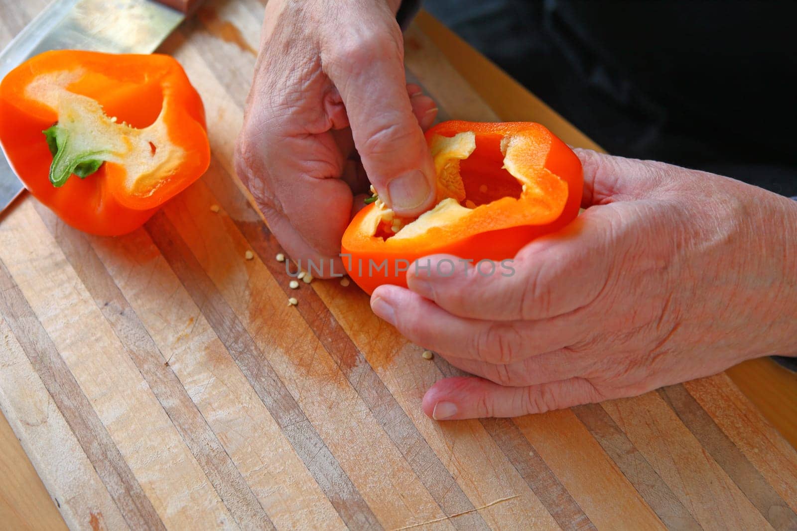 A senior man removes seeds from an orange bell pepper with room for text