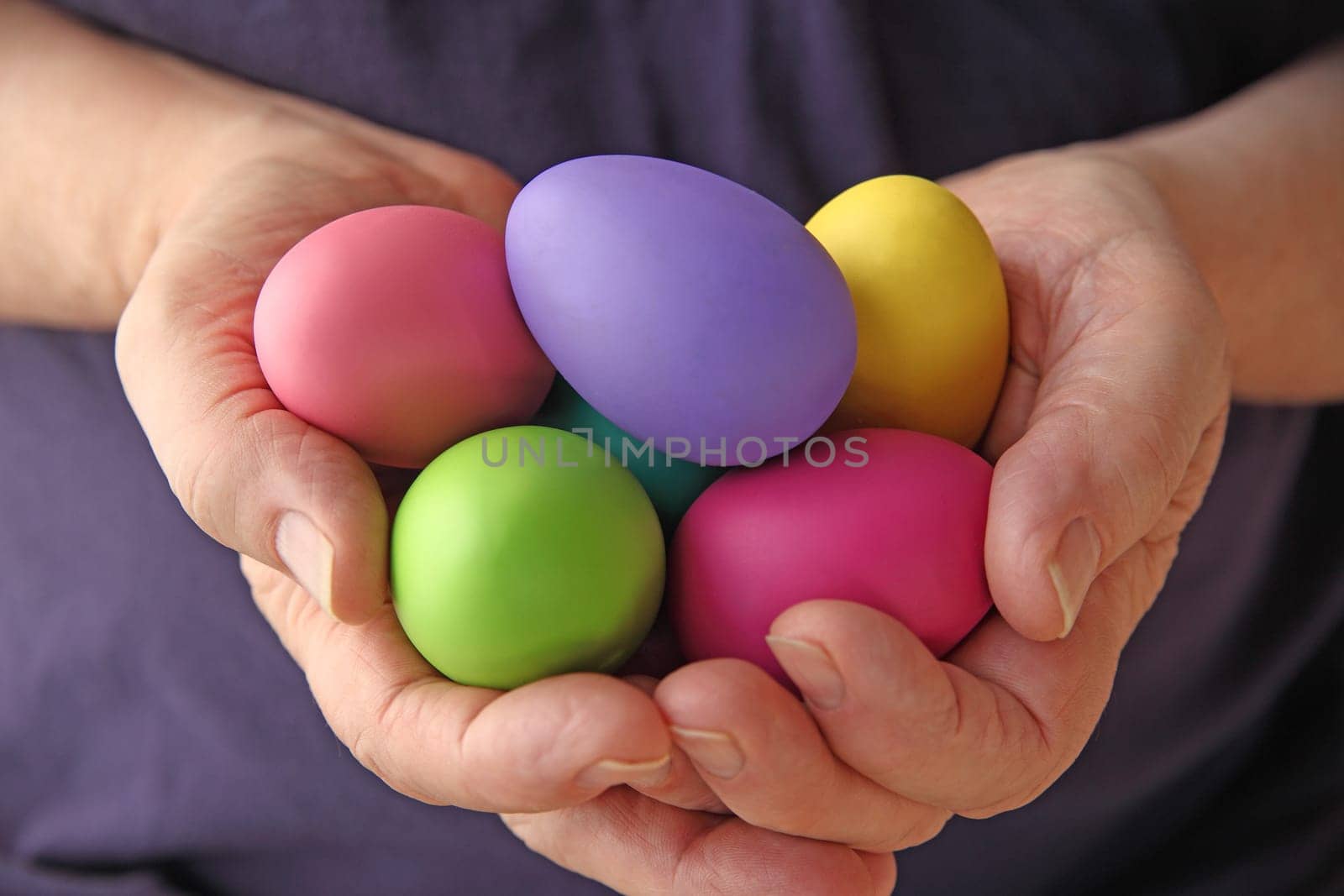 A man holds several brightly colored Easter eggs