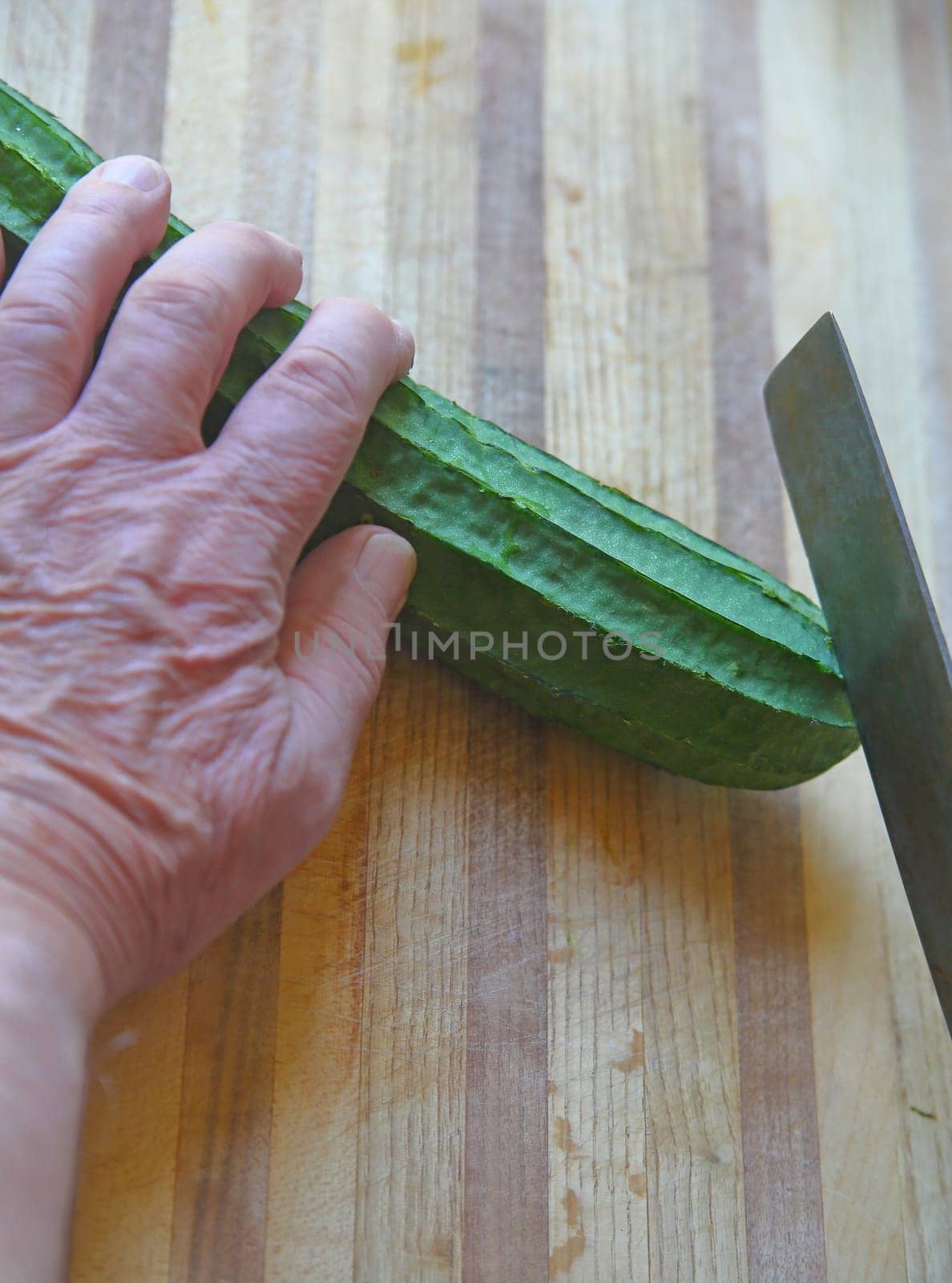 An older man prepares Chinese silk squash on a cutting board with copy space