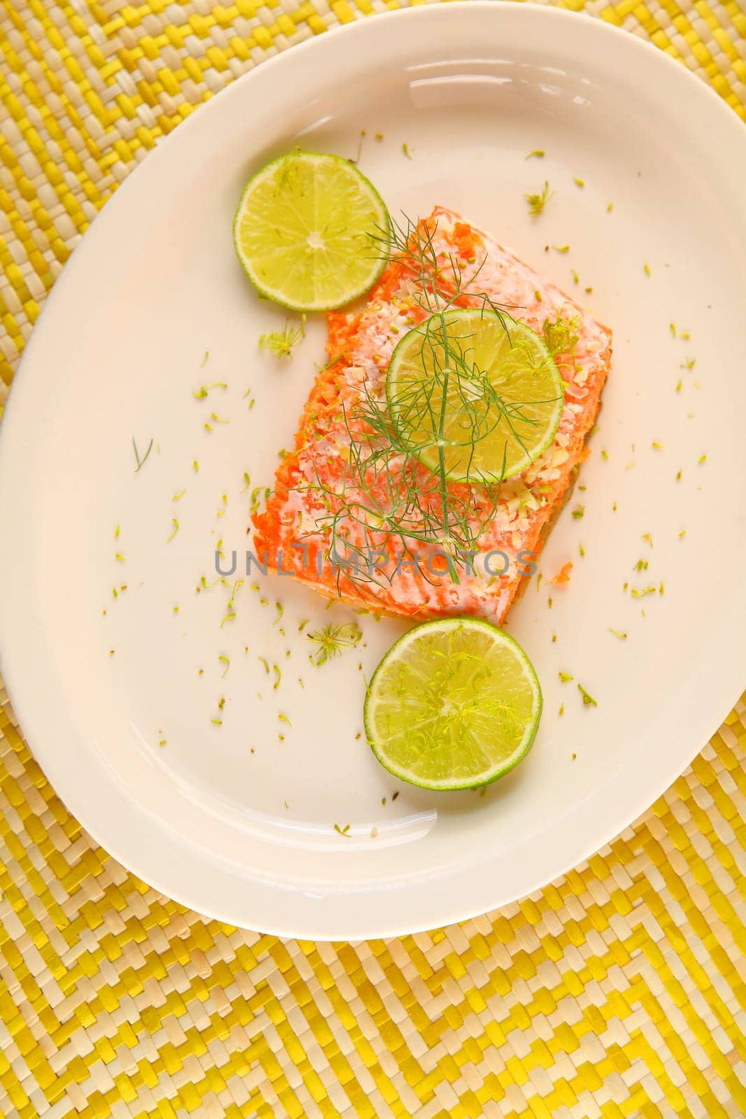 Overhead of salmon portion with garlic butter, fresh dill and lime slices