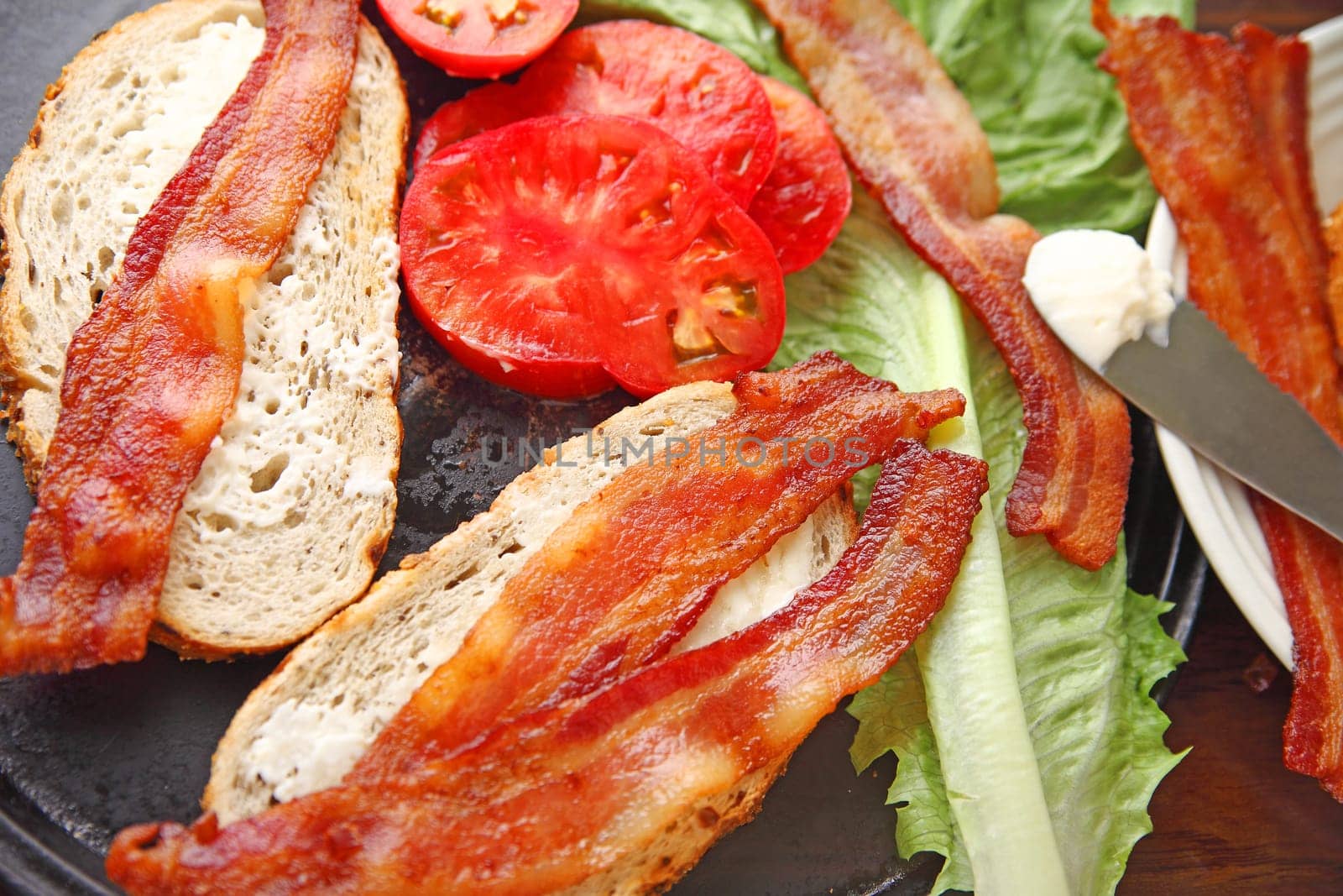 All the items needed to make a bacon, lettuce and tomato sandwich on onion rye bread