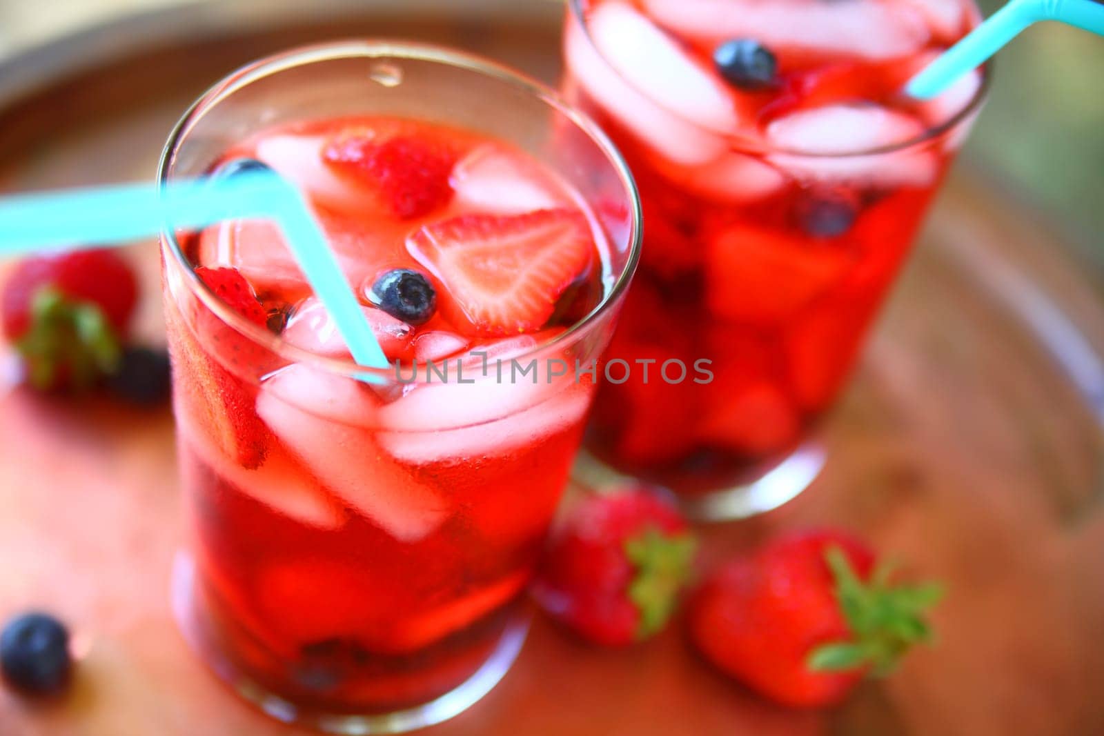 Two glasses of icy water with strawberries and blueberries
