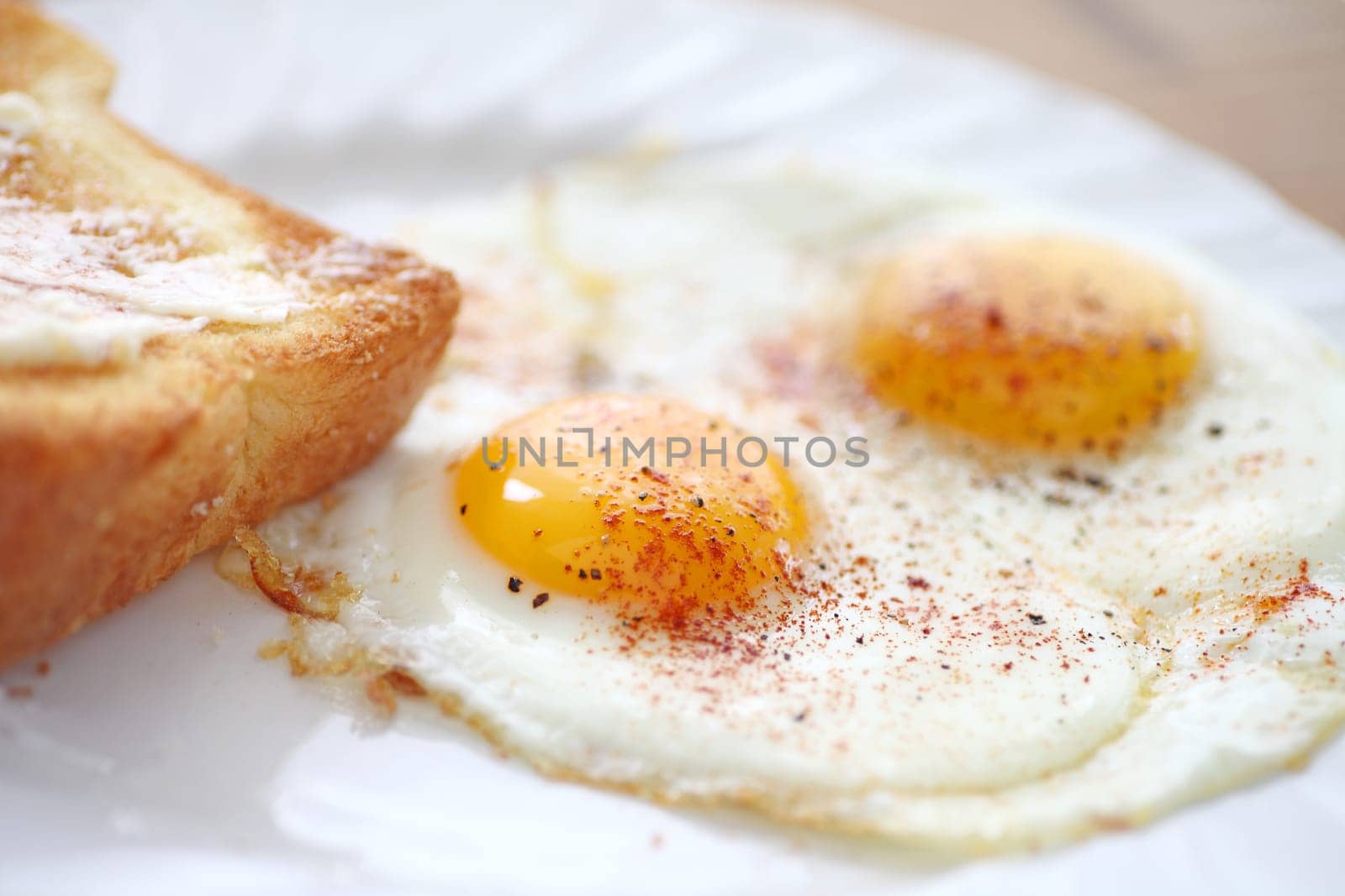 two fried eggs sunny side up, sprinkled with smoked paprika and black pepper, toast alongside