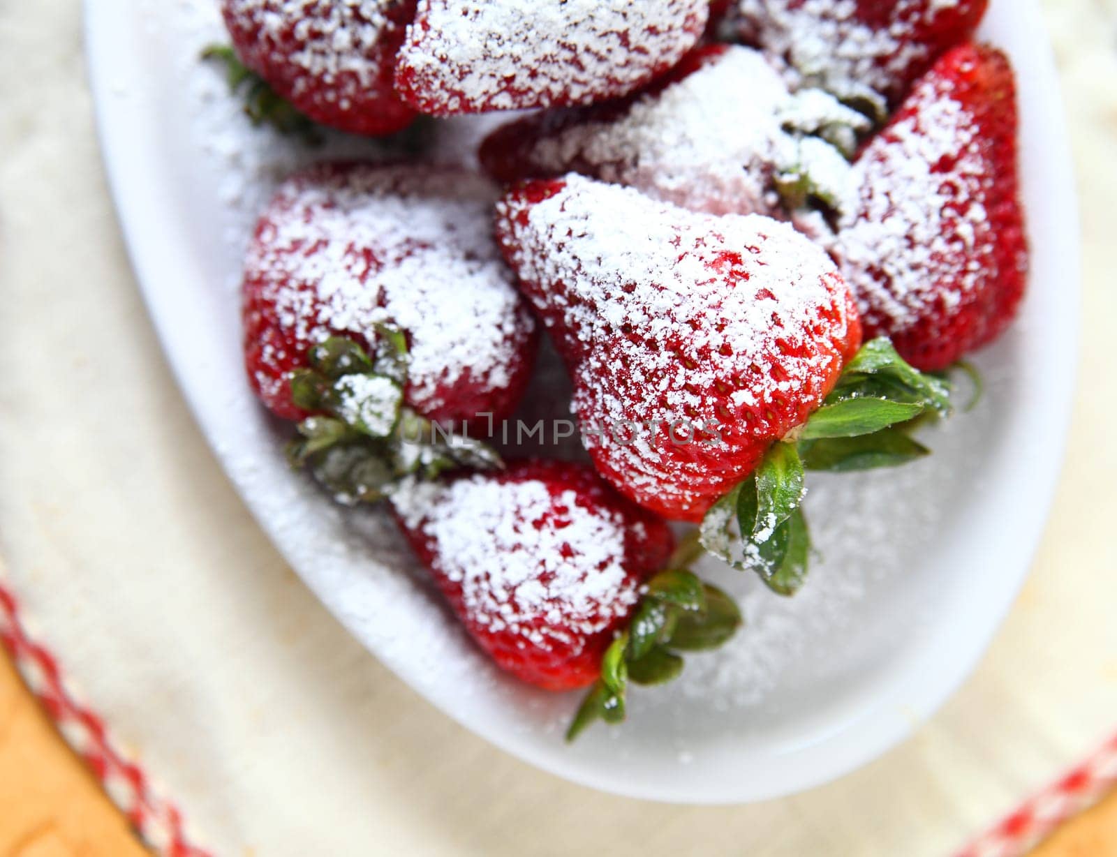 Fresh strawberries with powdered sugar in a white dish
