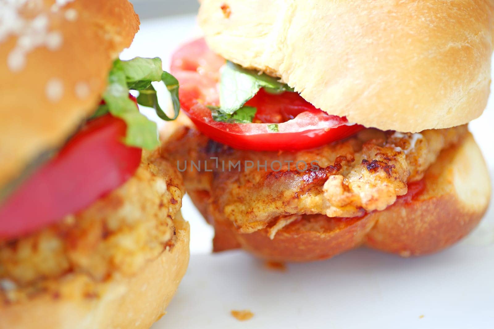 Battered and fried pork cutlets with tomato and chopped lettuce on bread rolls