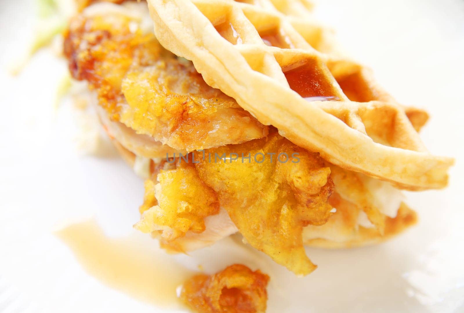 Fried chicken slices enclosed in a waffle with coleslaw and syrup