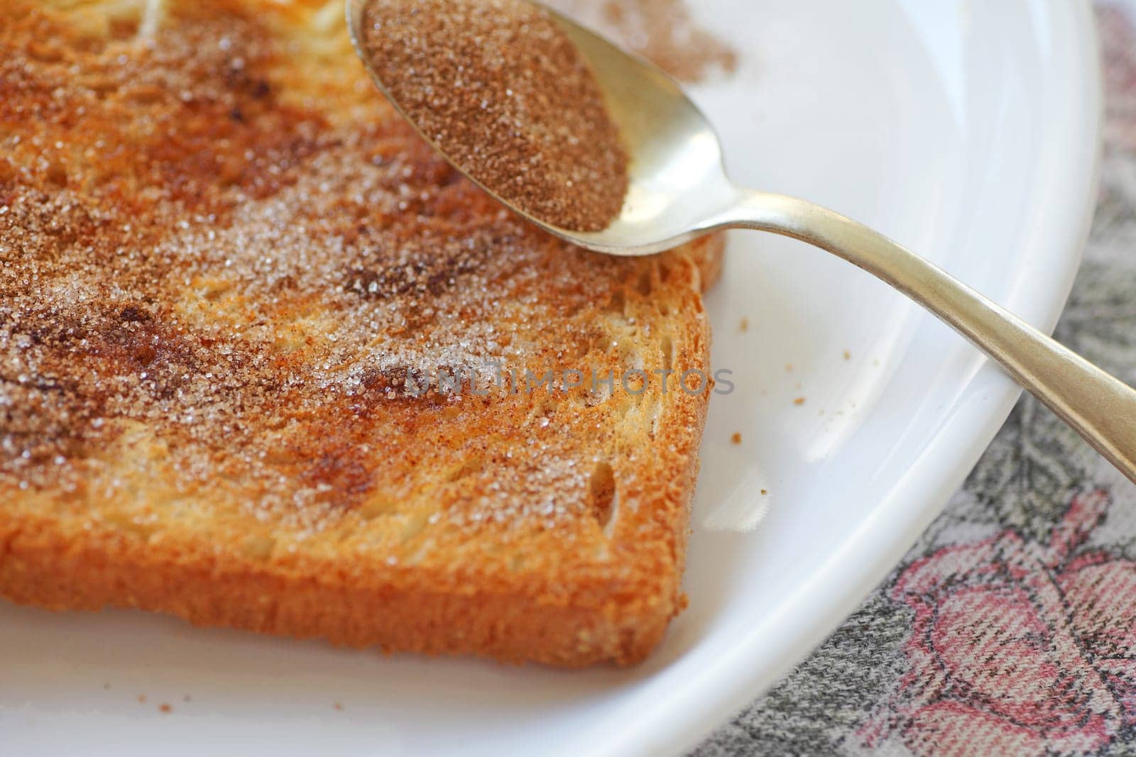 closeup of a slice of buttered toast with cinnamon sugar sprinkled over