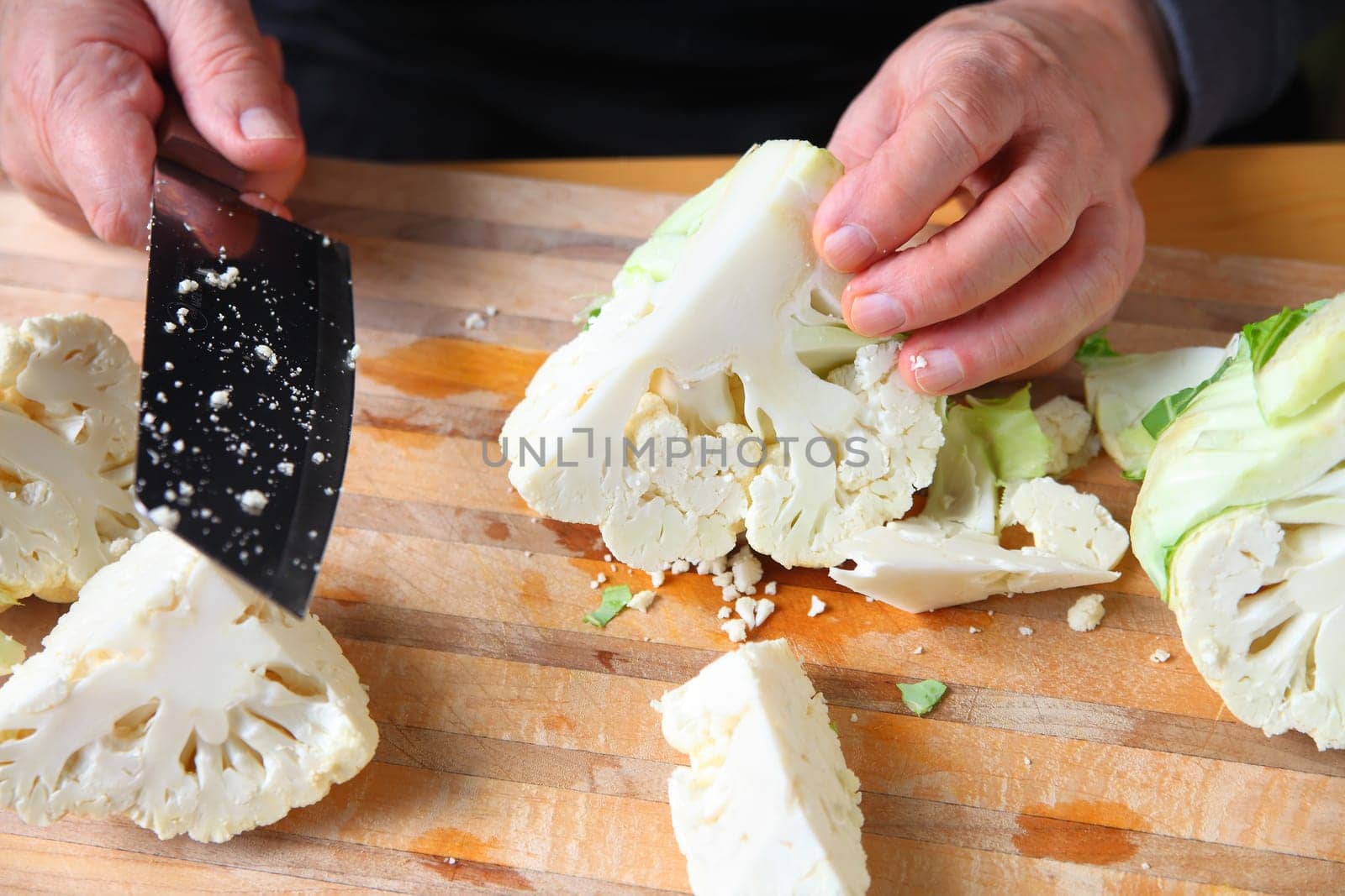 A man cuts up a cauliflower on a chopping board
