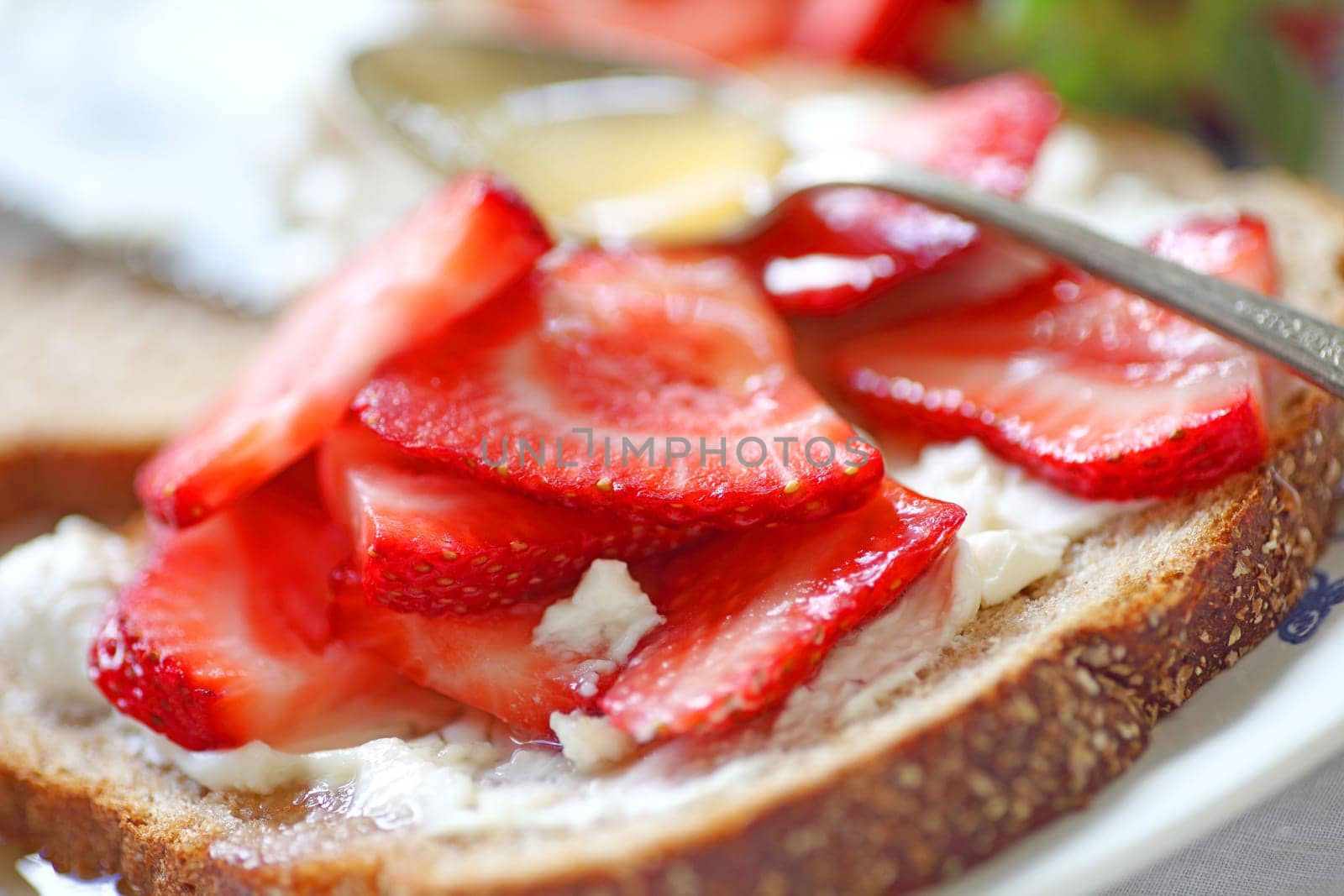 Sliced strawberries with cream cheese on whole wheat bread with honey