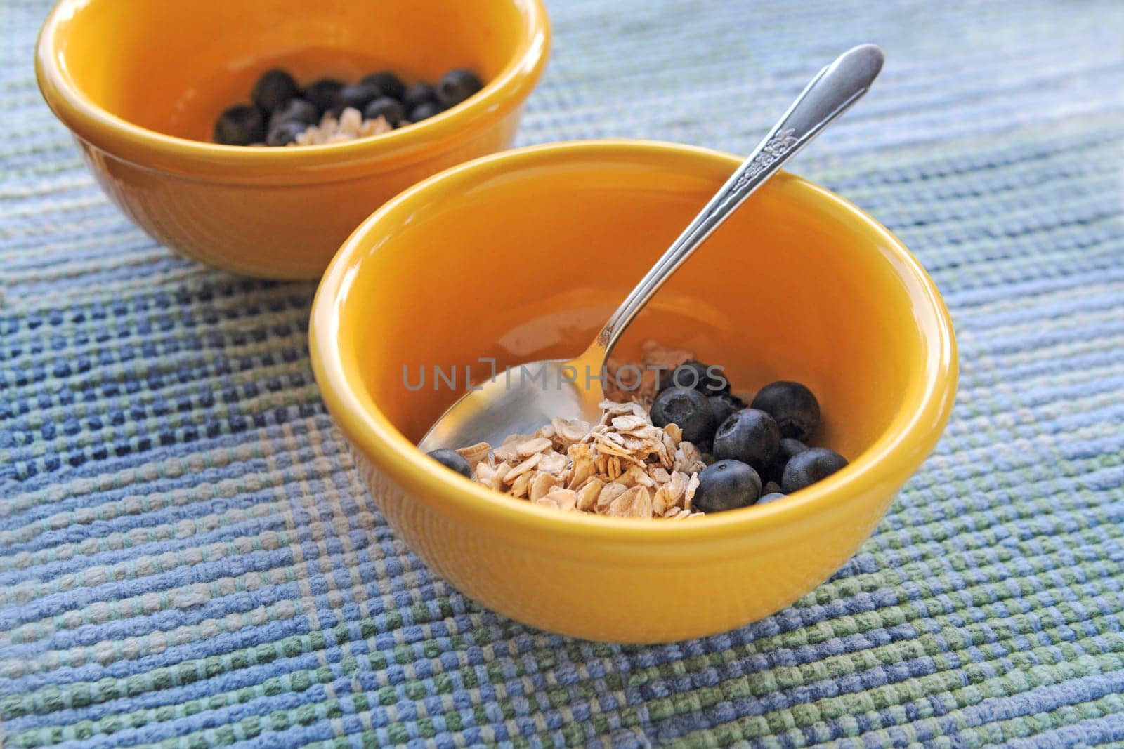 Uncooked oatmeal in yellow bowls with fresh blueberries and copy space