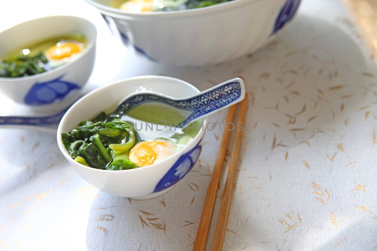 Large serving bowl with smaller bowls of spinach soup and poached eggs