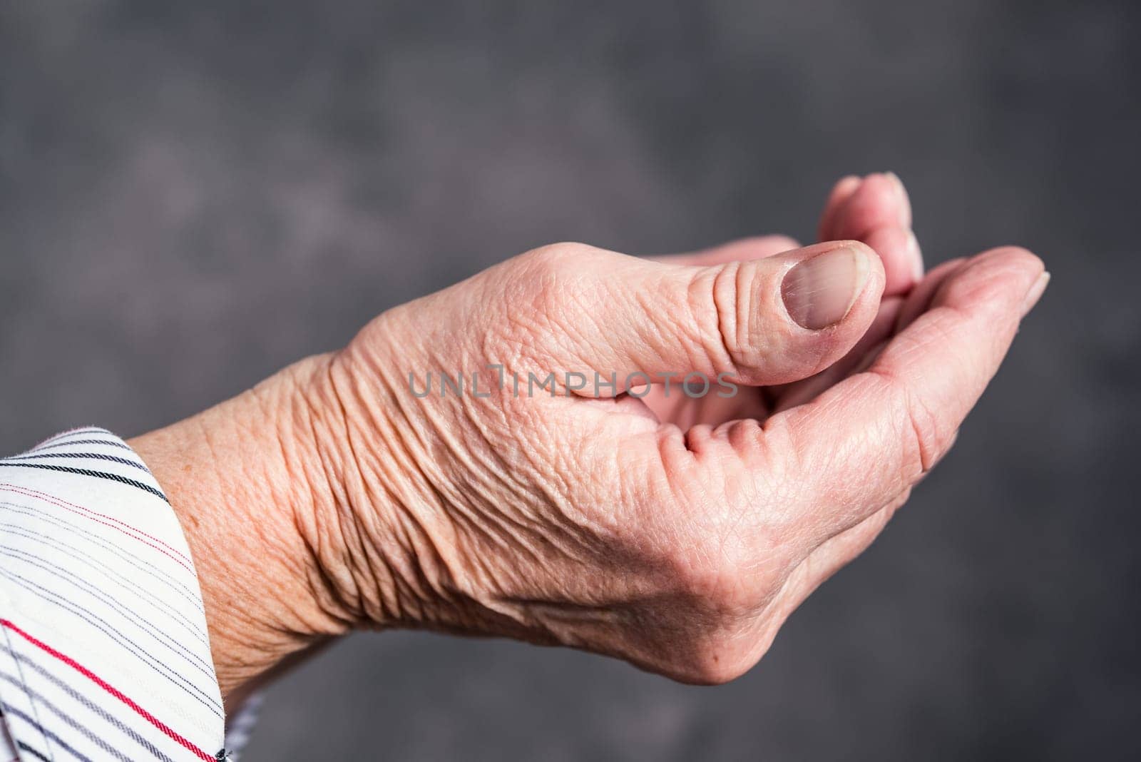 open hands of  elderly woman in front of dark background