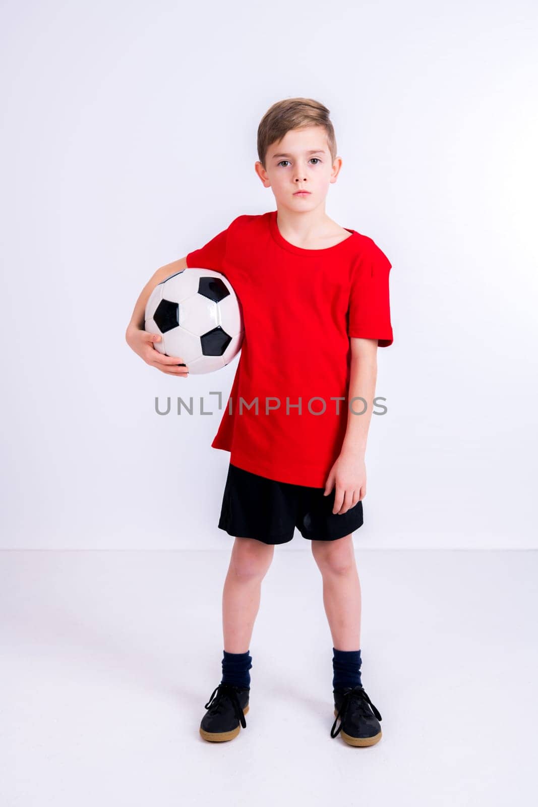boy in red shirt with soccer ball in front of white background