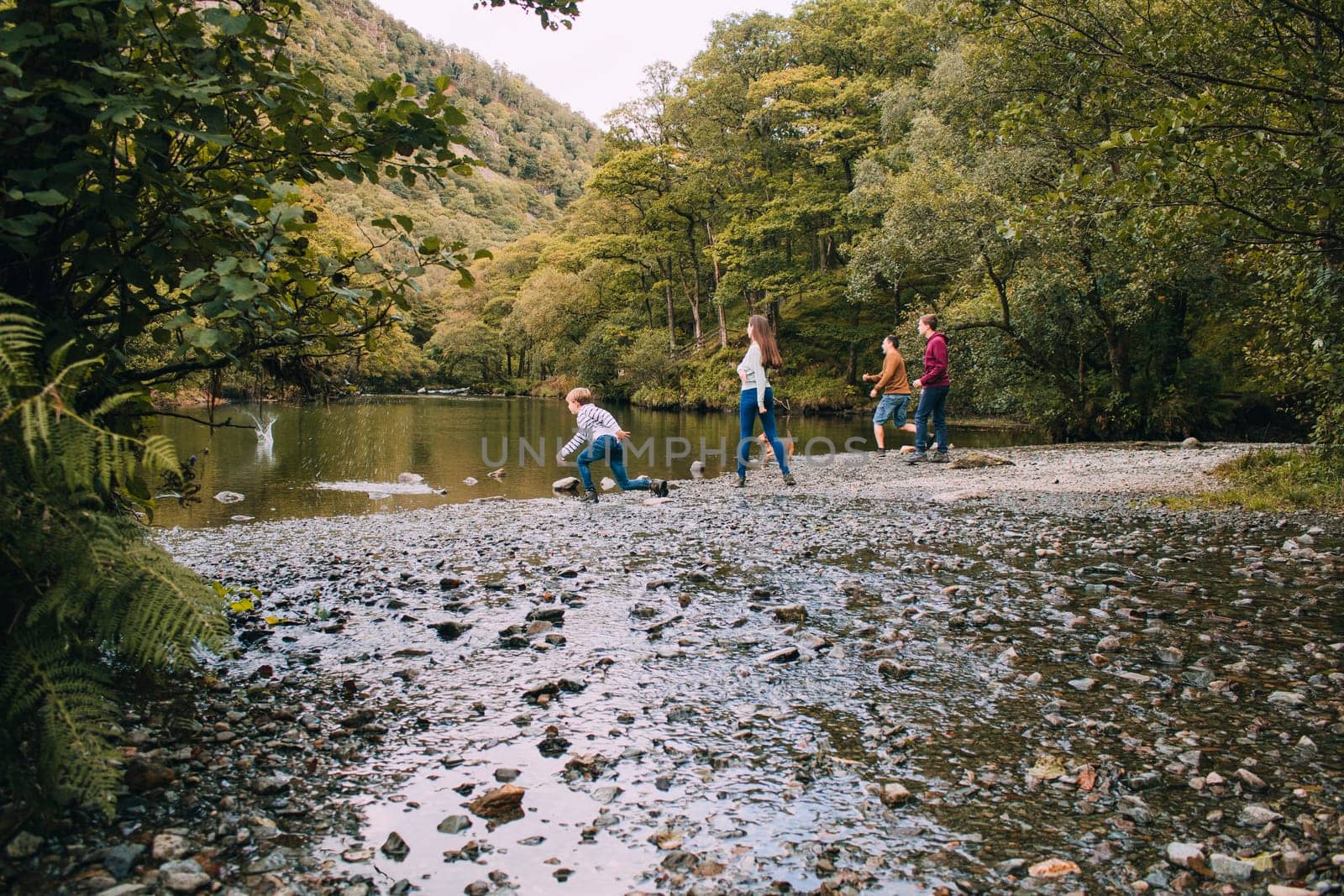 Family are skimming stones on a lake in the Lake District.