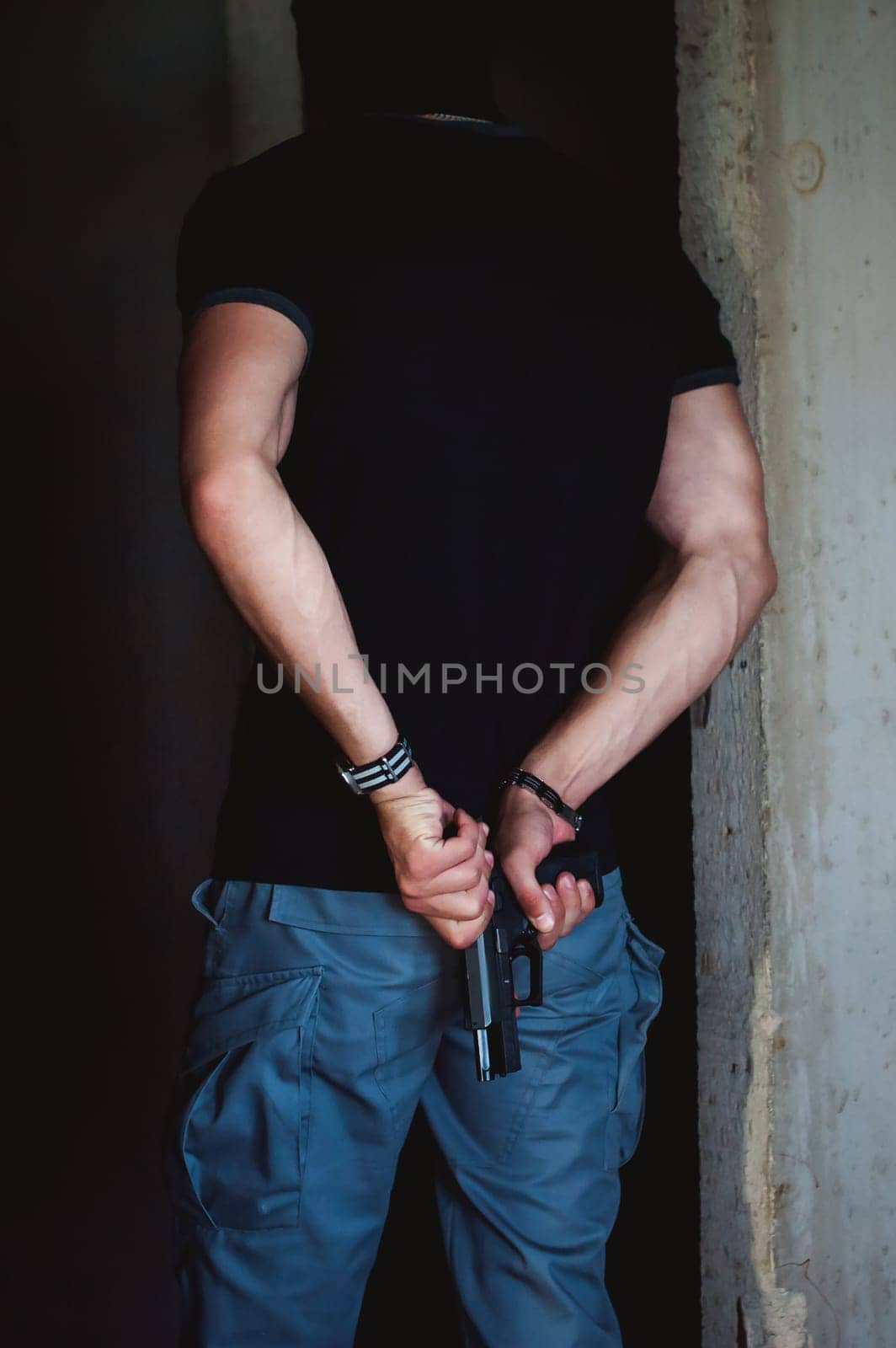 Athletic man, a dangerous gangster, reloads a gun behind his back
