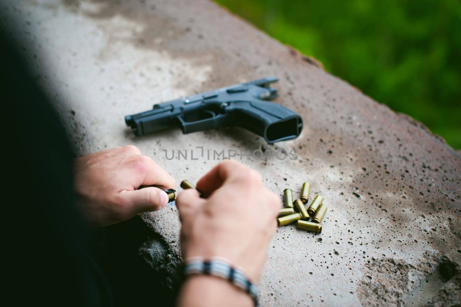 Man charges clip of pistol with bullets. Photo hands of paramilitary, reloading weapons. Preparation for shooting