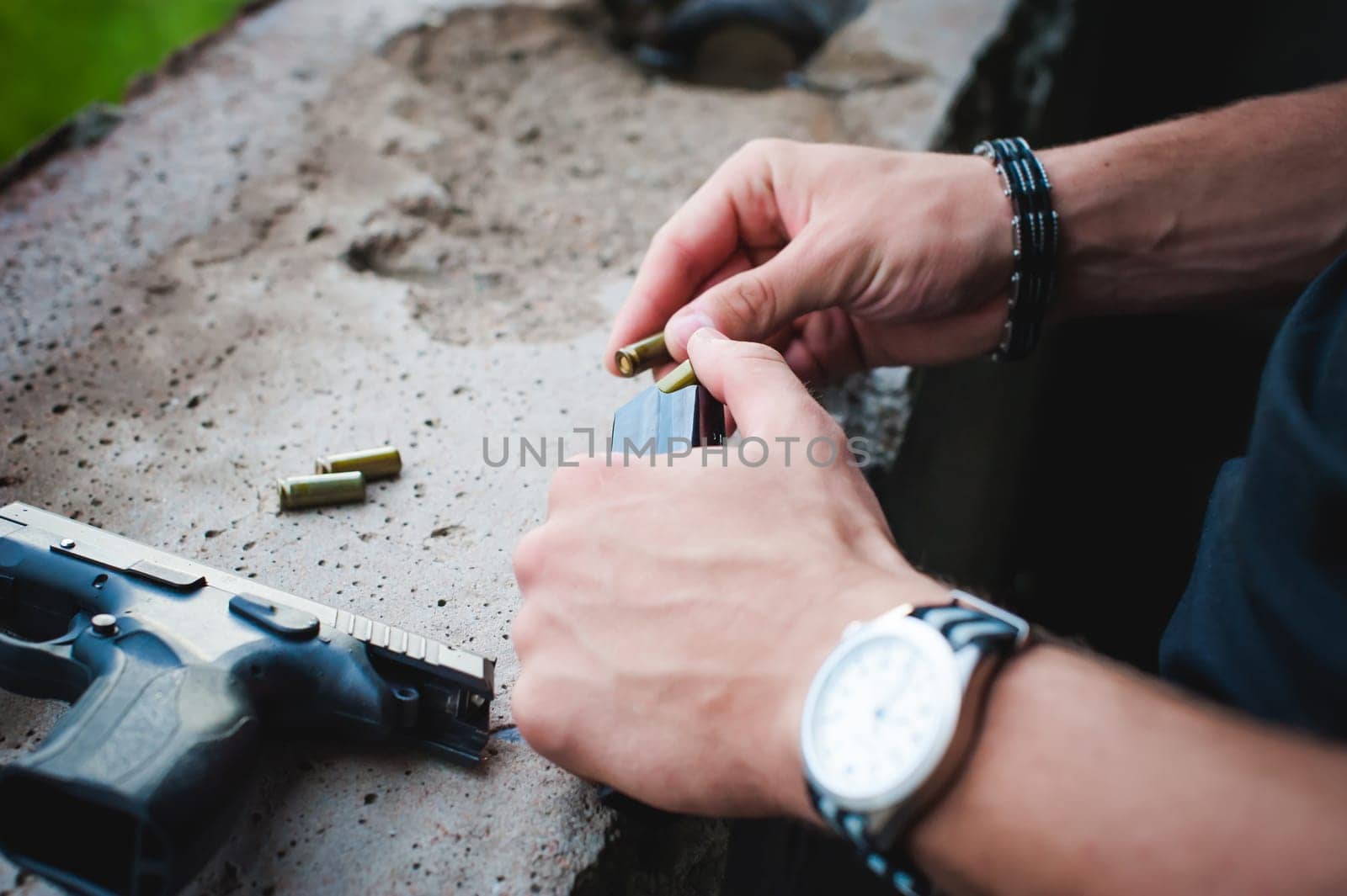 Man charges clip of pistol with bullets. Photo hands of paramilitary, reloading weapons. Preparation for shooting