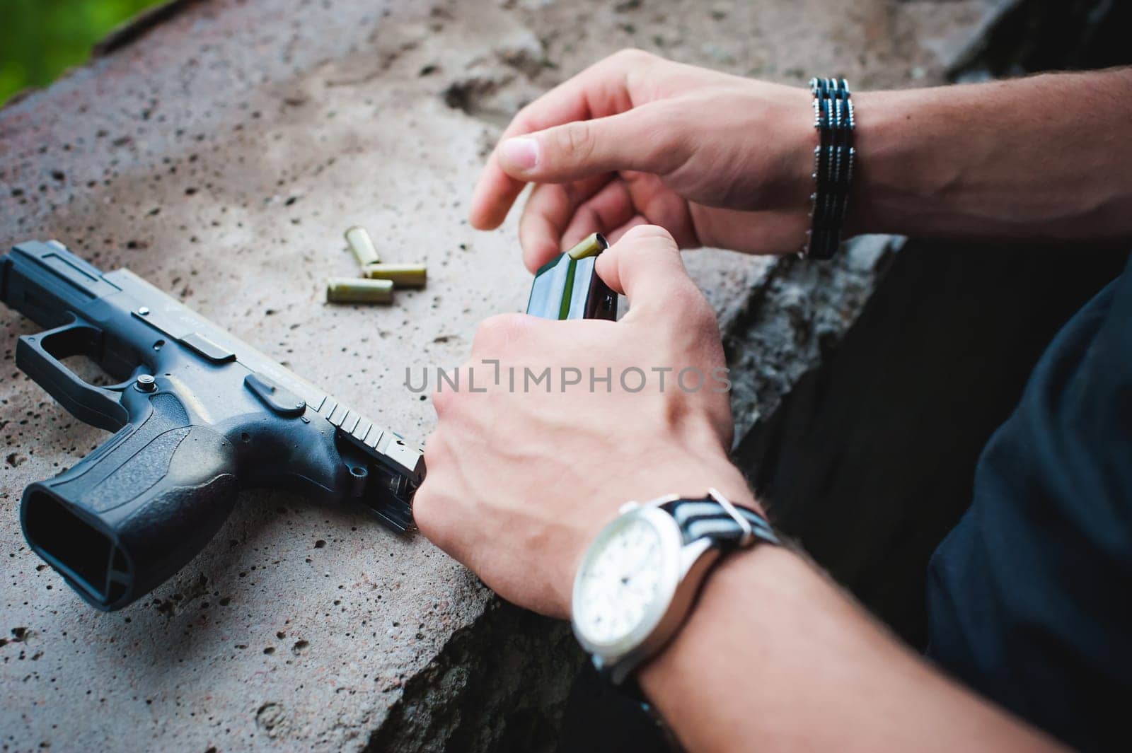 Man charges clip of pistol with bullets. Photo hands of paramilitary, reloading weapons. Preparation for shooting