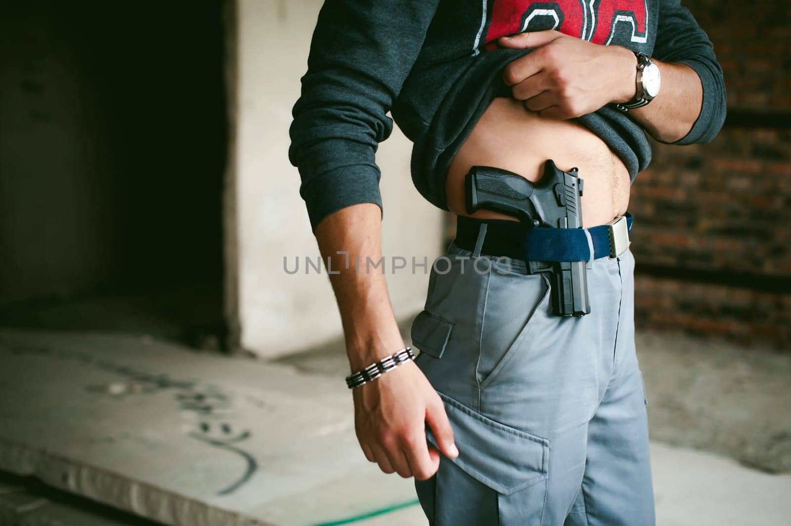 young athletic man holding a gun behind his belt.
