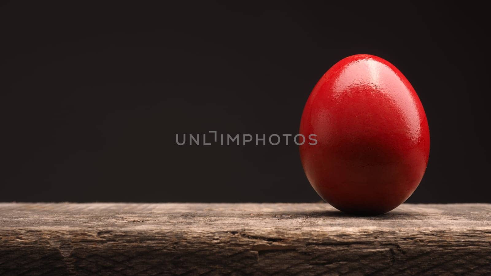 Red Easter egg on a rustic wooden table with space for text or image, Happy Easter background
